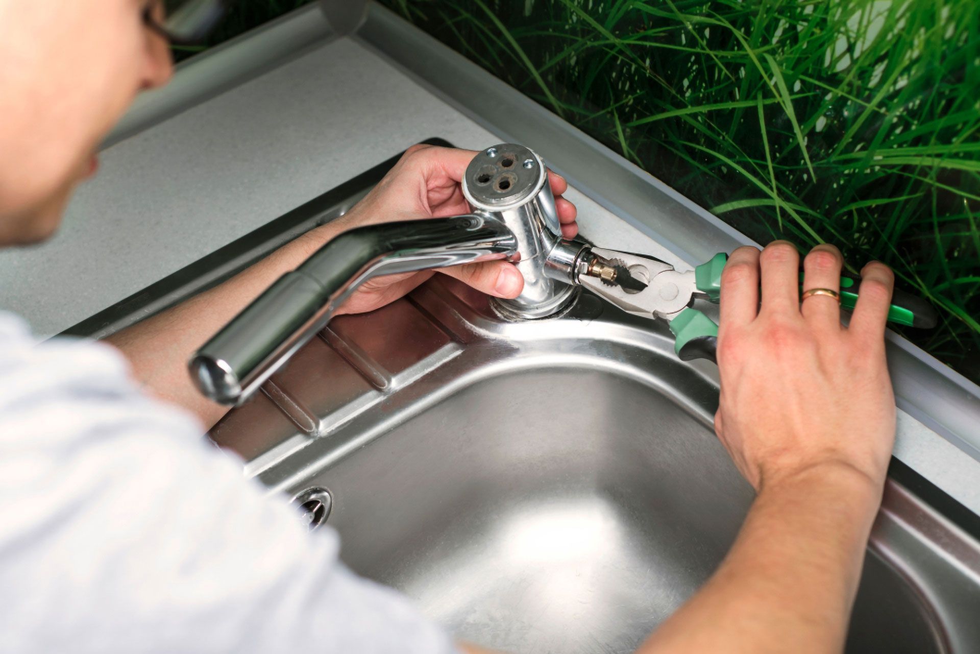 Person Using Pliers to Work on a Chrome Faucet in a Stainless Steel Sink — Full On Plumbing & Gas in Nightcliff, NT