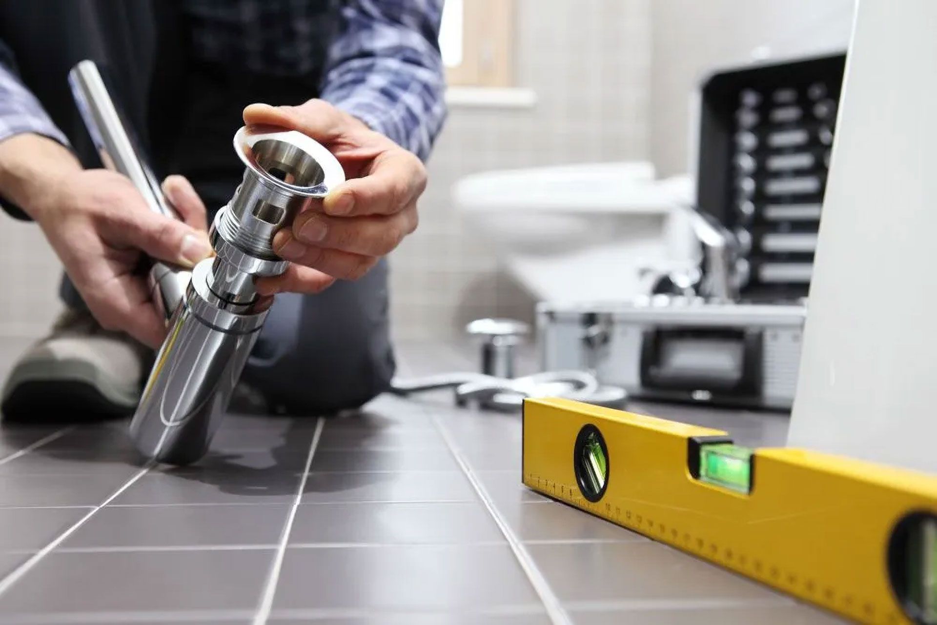 Plumber Installing Sink Drain in Bathroom With Tools and Level on the Floor — Full On Plumbing & Gas in Parap, NT