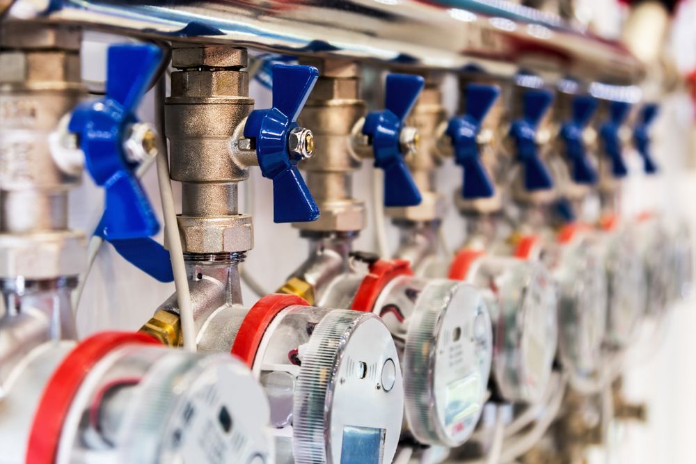 Close-up of a Row of Water Meters With Blue and Red Valves Connected to Pipes — Full On Plumbing & Gas in Casuarina, NT