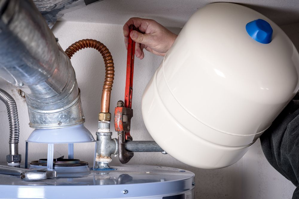 A Person Uses a Wrench to Work on a Water Heater and Its Components — Full On Plumbing & Gas in Winnellie, NT