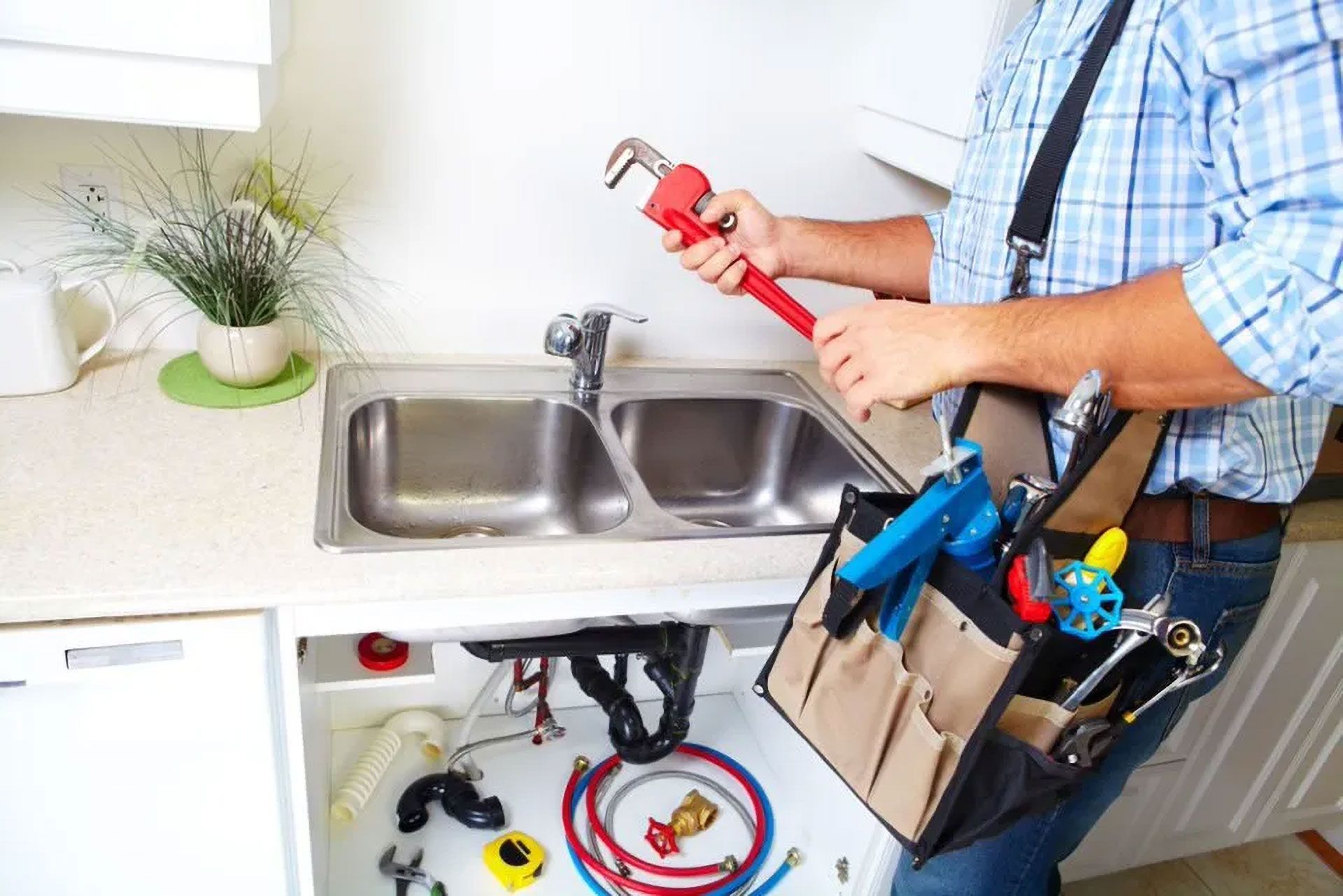 Plumber Working on a Sink, Holding a Wrench, With a Tool Bag, in a Kitchen — Full On Plumbing & Gas in Winnellie, NT