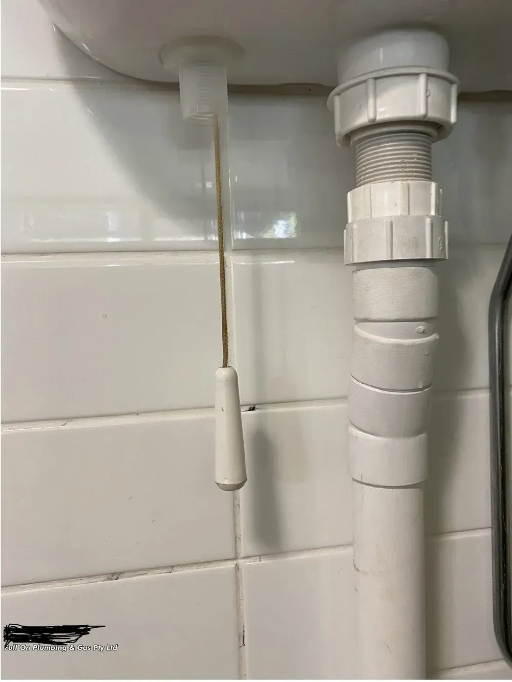 White Sink Drain Stopper Pull Cord Next to a White Plastic Drain Pipe — Full On Plumbing & Gas in Nightcliff, NT