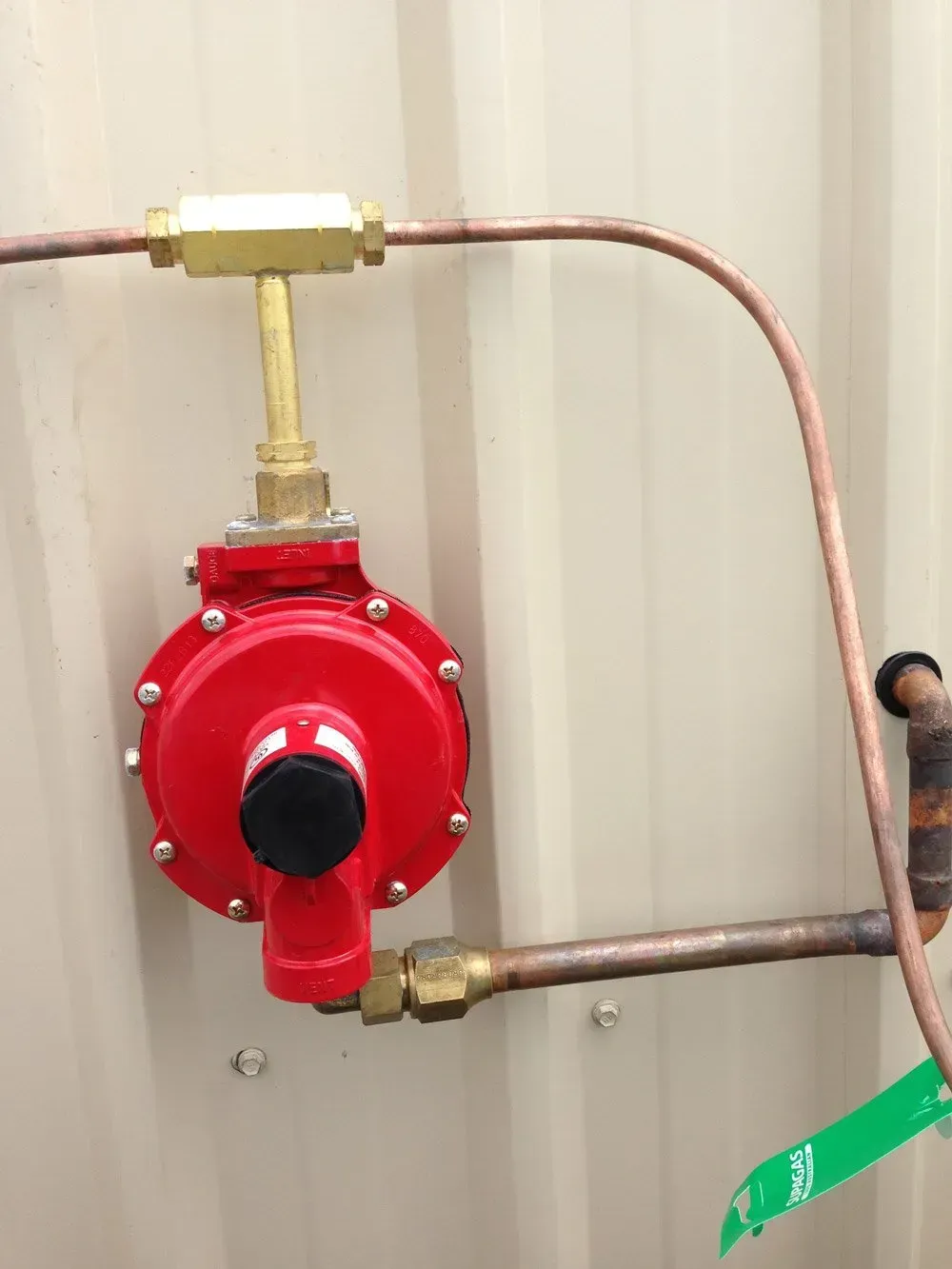 Red Gas Regulator With Copper Pipes Against a Metal Wall — Full On Plumbing & Gas in Winnellie, NT