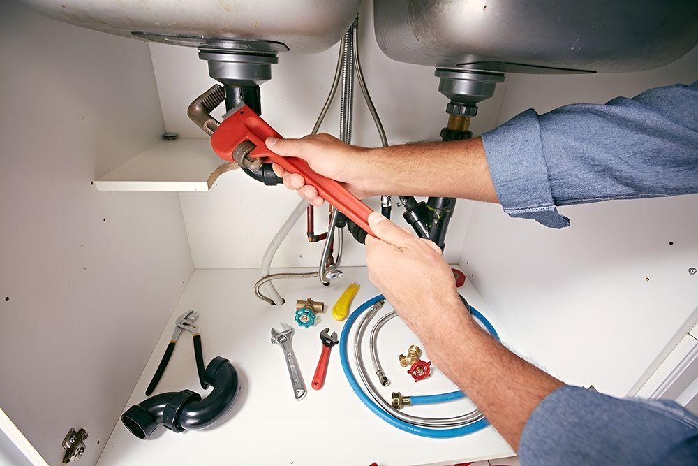 Plumber Working Under a Kitchen Sink, Using a Wrench — Full On Plumbing & Gas in Winnellie, NT