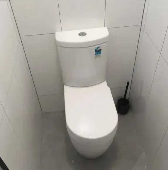 White Toilet in a Small Bathroom With Gray Floor and White Tiled Walls — Full On Plumbing & Gas in Winnellie, NT