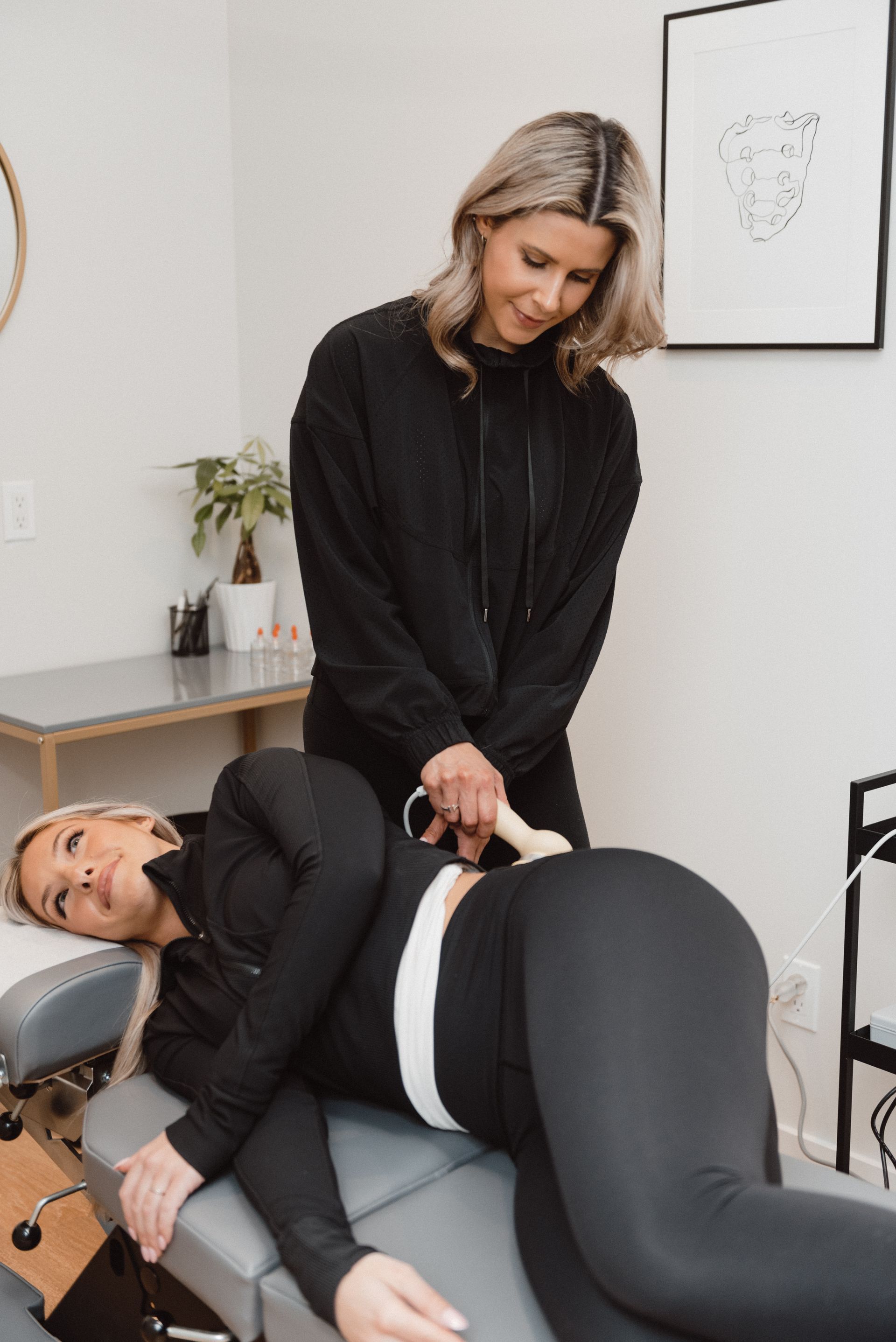 A woman is laying on a table getting a massage from another woman.