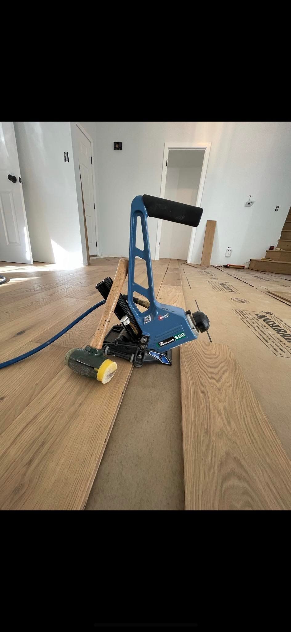 A blue flooring saw cutting wood planks in a room.