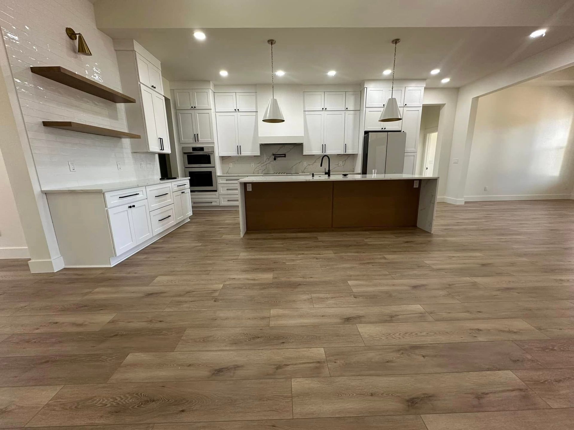 Modern kitchen with white cabinets, wood island, stainless steel appliances, and wood flooring.