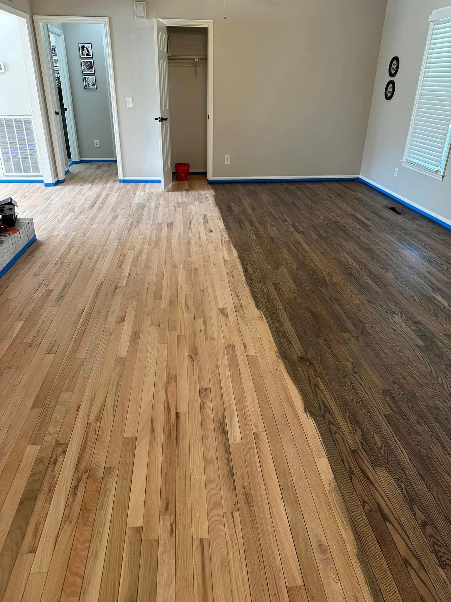 Hardwood floor, partially stained dark brown, showing unfinished, light wood next to finished. Interior room setting.