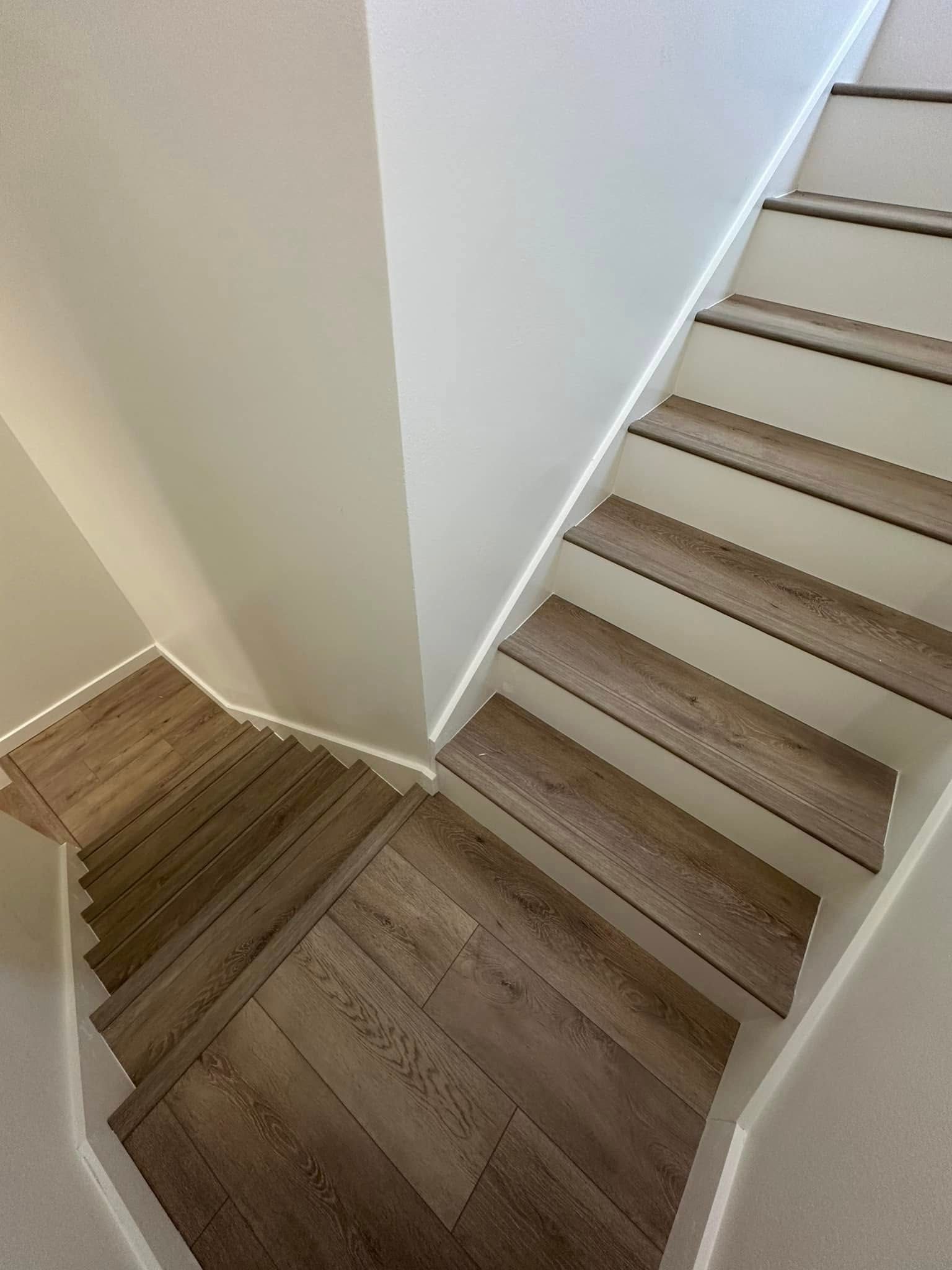 Staircase with light wood steps, white walls, and LED strip lighting along the edges.