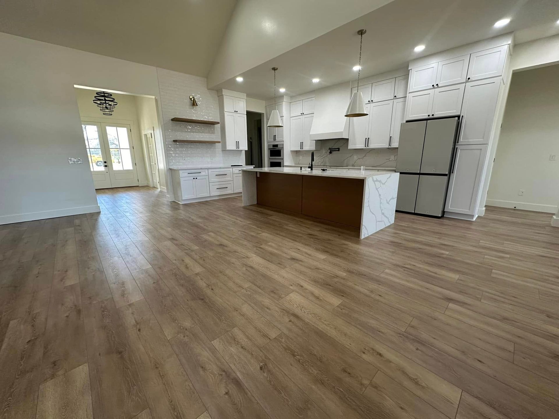 Spacious kitchen with wood floors, white cabinets, island, and large windows.
