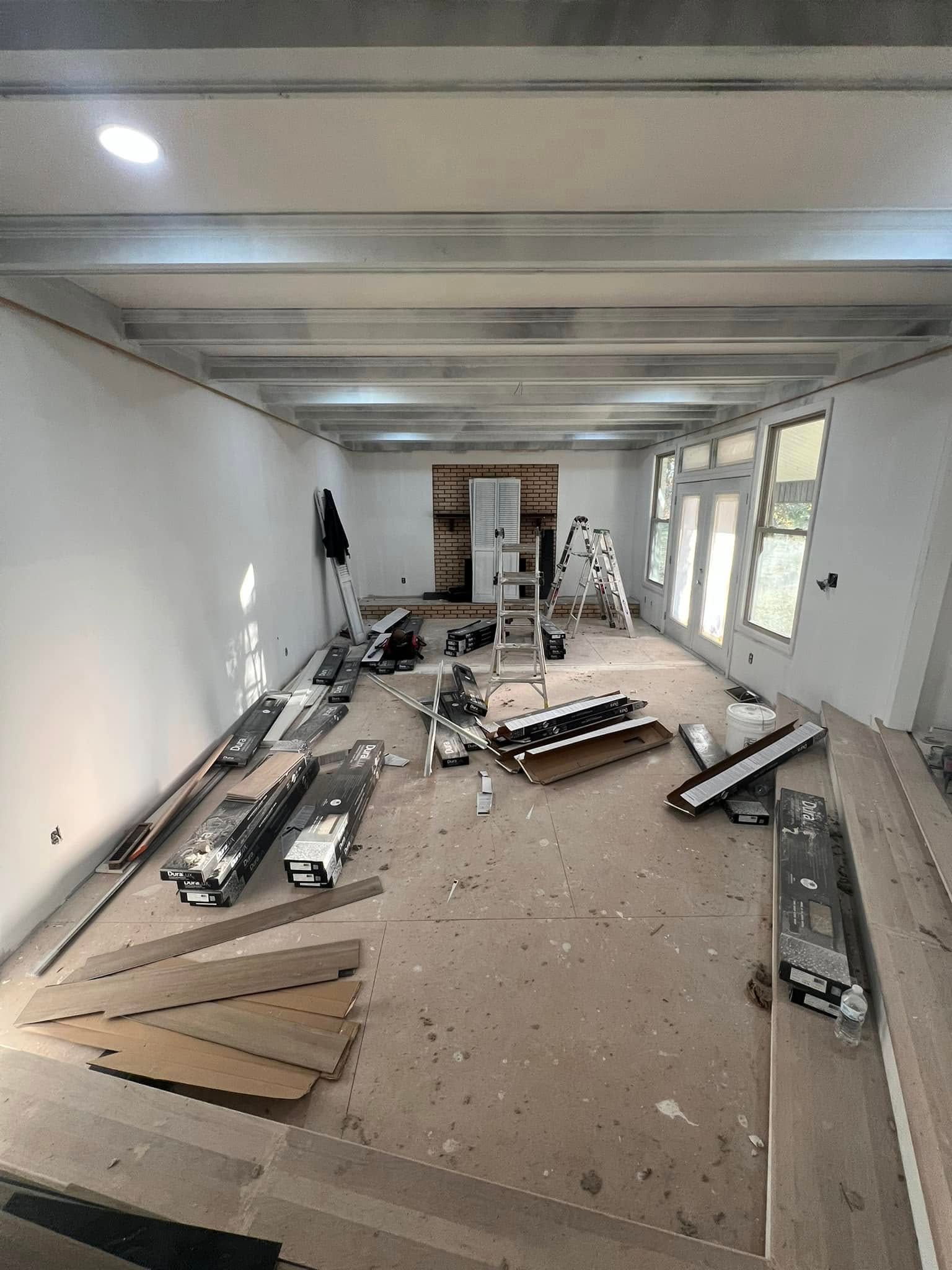 Room under construction with exposed beams, tools, and flooring materials.