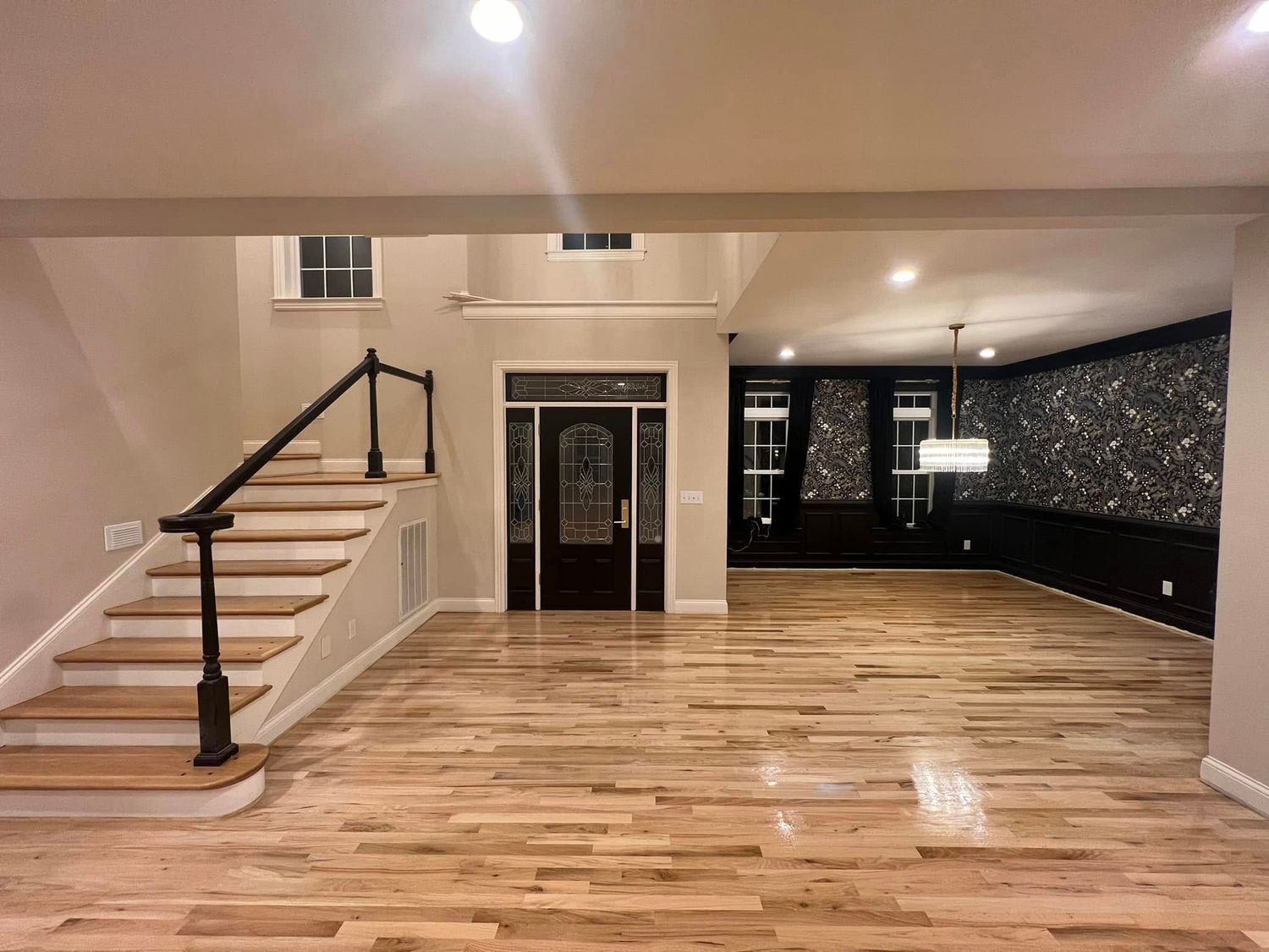 Wooden-floored foyer with stairs, dark door, and feature wall.