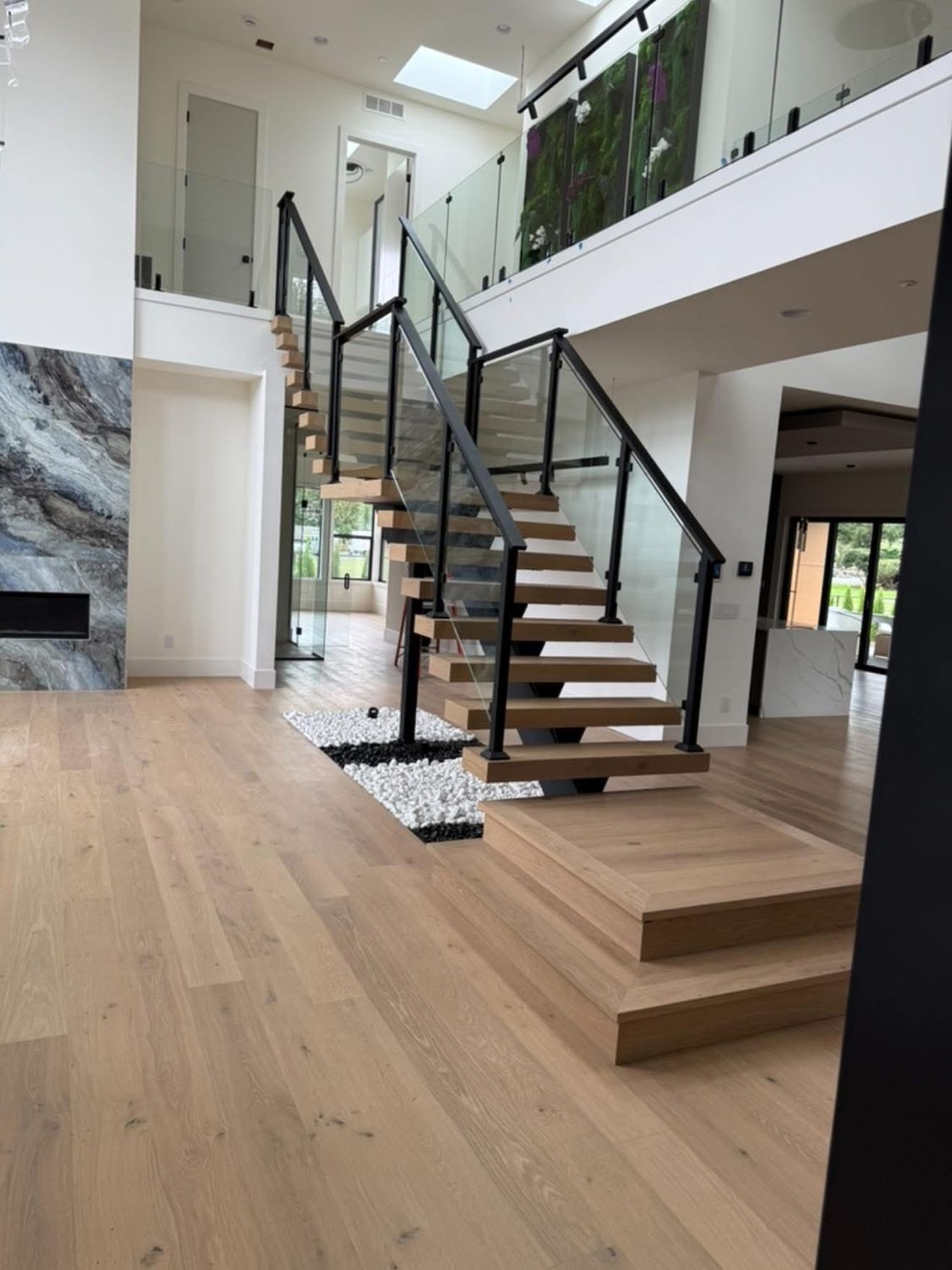 Modern staircase with glass panels and wooden steps in a light-filled interior.
