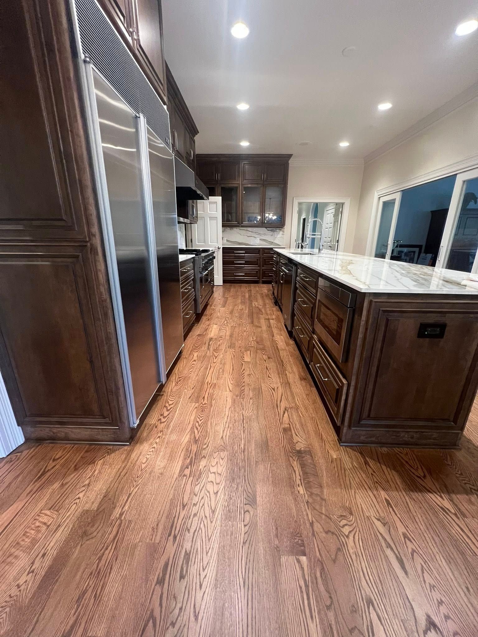 Spacious kitchen with dark wood cabinets, stainless steel appliances, and a large island with marble countertops.