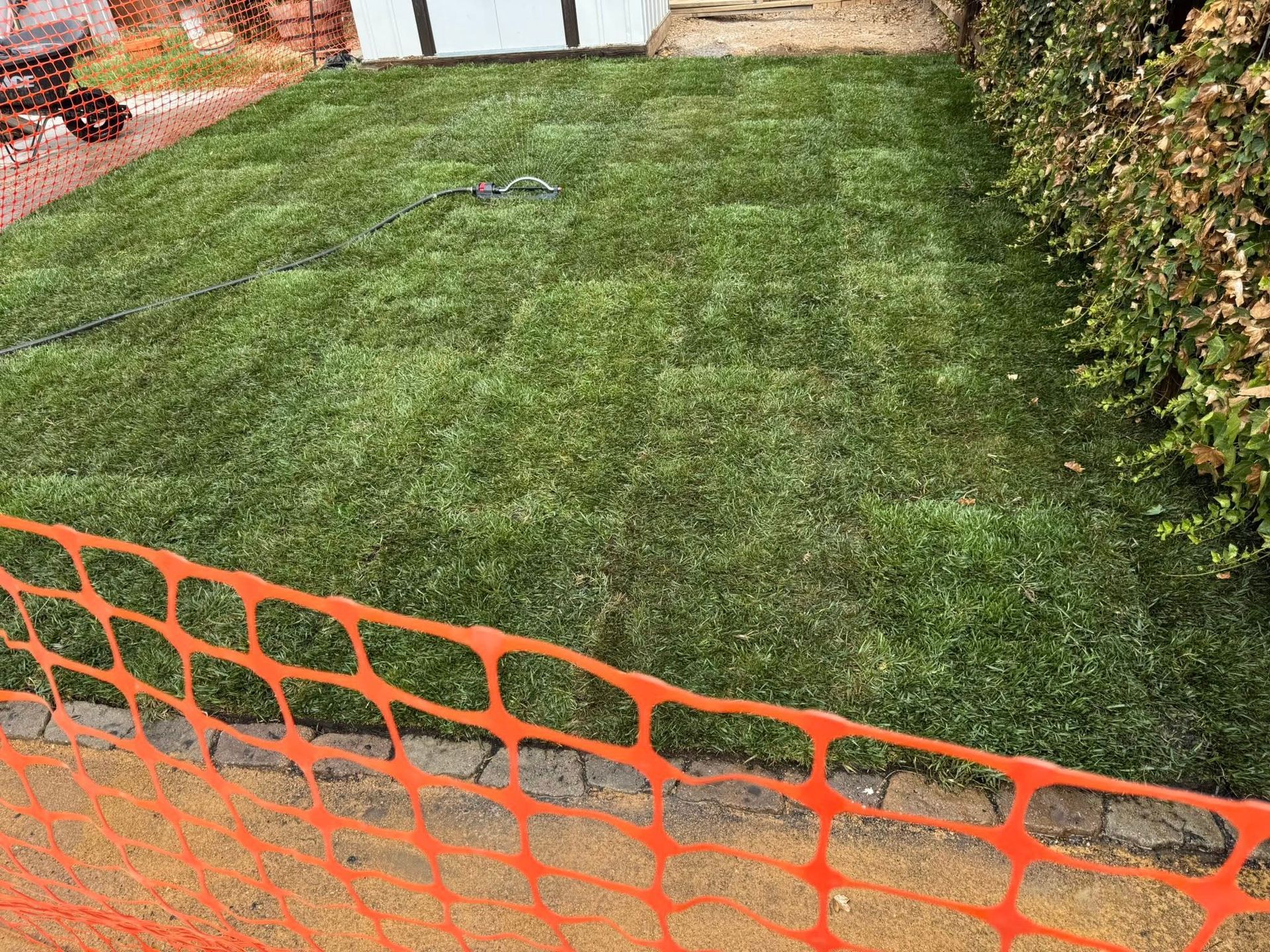 Plumber in red overalls and blue gloves, using a wrench on pipes near a boiler.