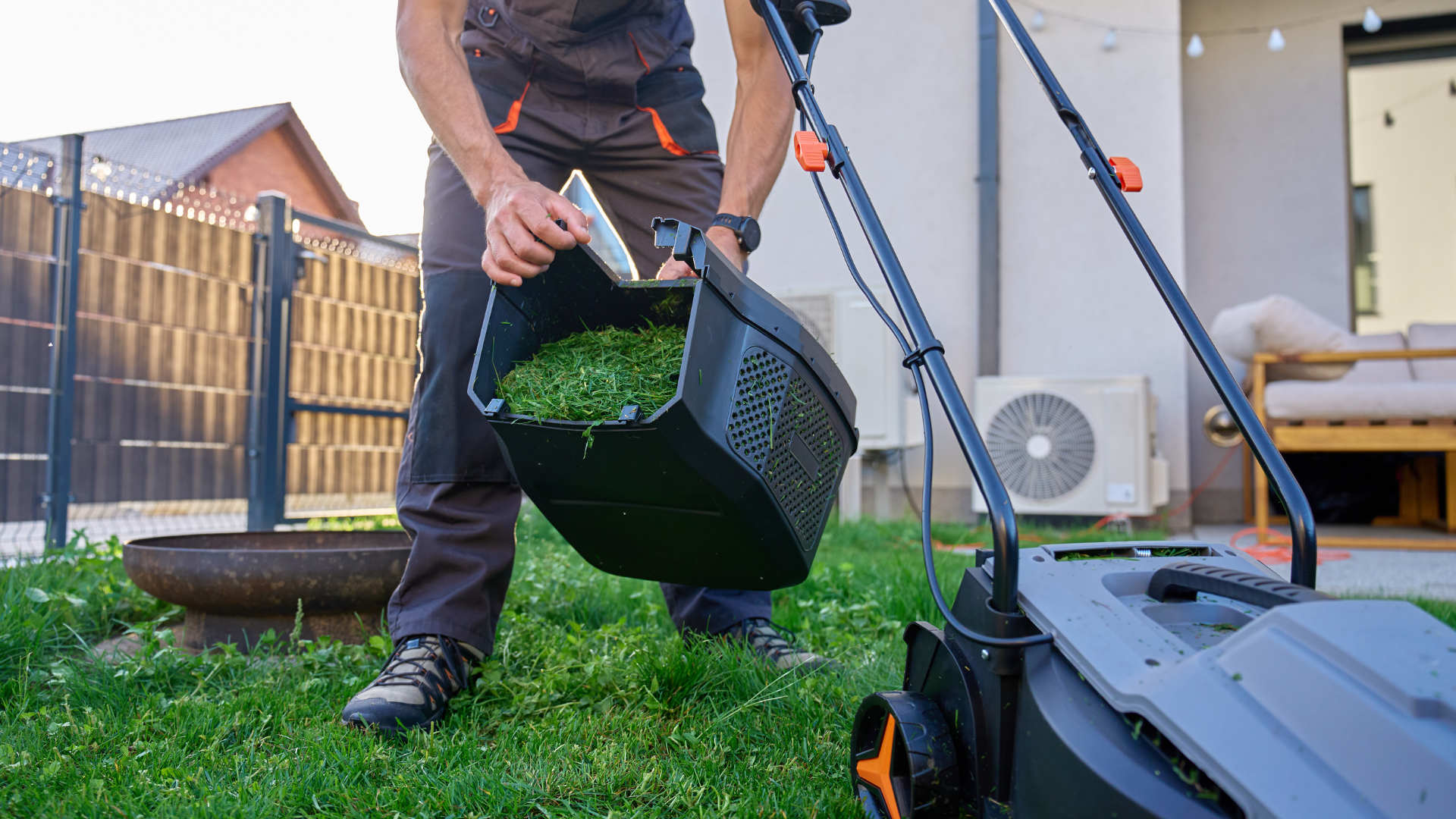 Two technicians in blue uniforms stand near an AC unit and tools outside a modern house with glass doors.