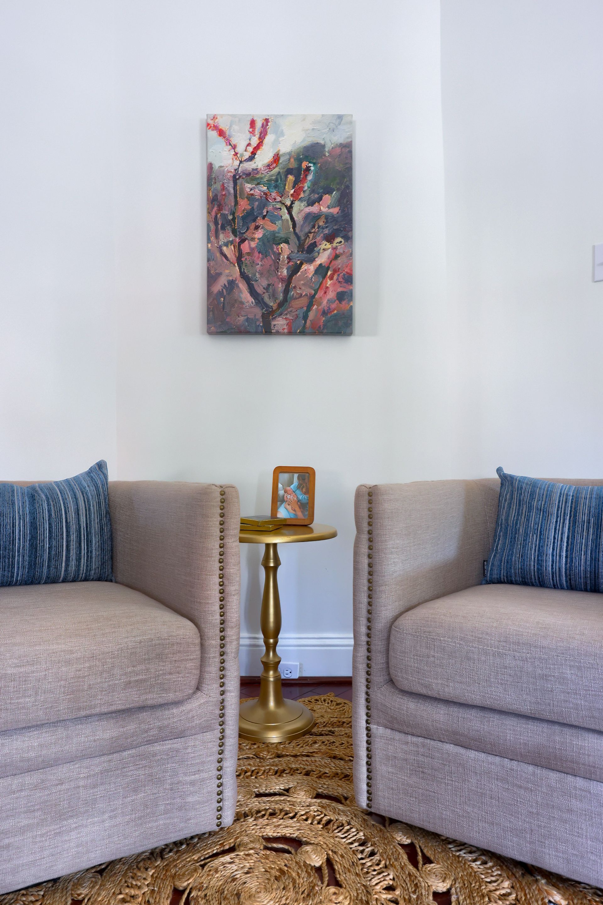 A living room with two chairs and a painting on the wall.