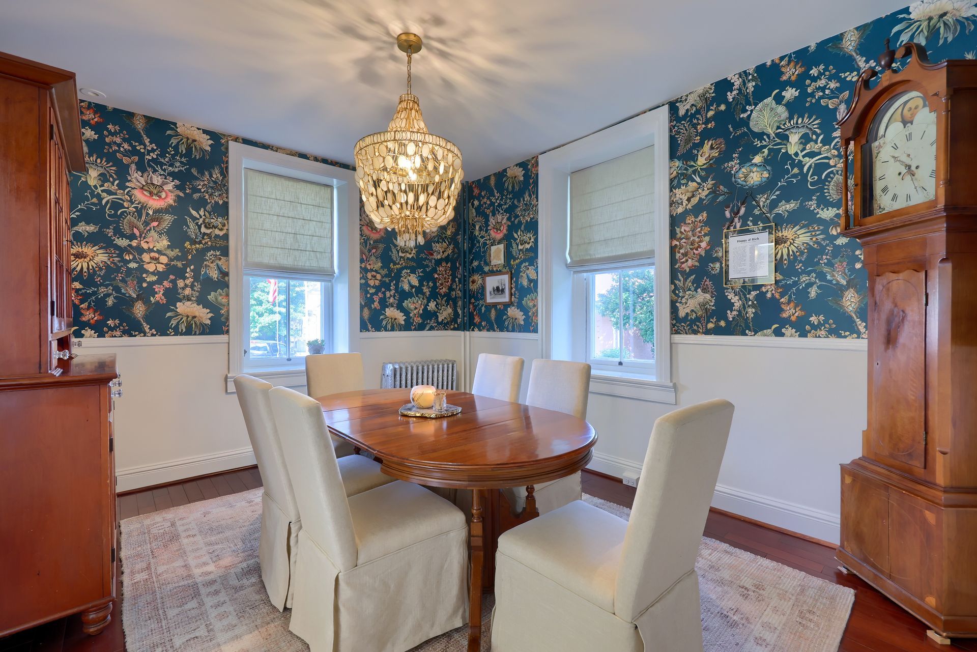 A dining room with a table and chairs and a grandfather clock.