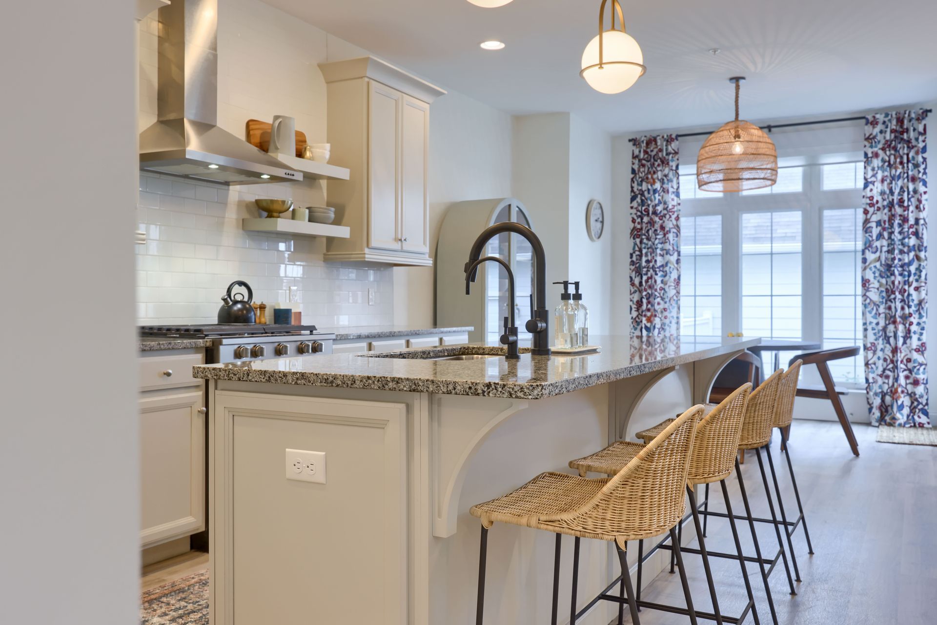 A kitchen with a large island and wicker bar stools.