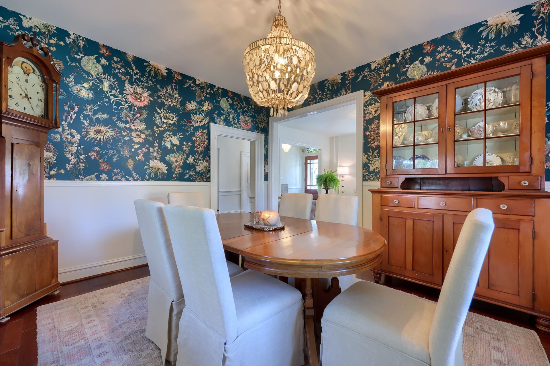 A dining room with a table and chairs and a clock