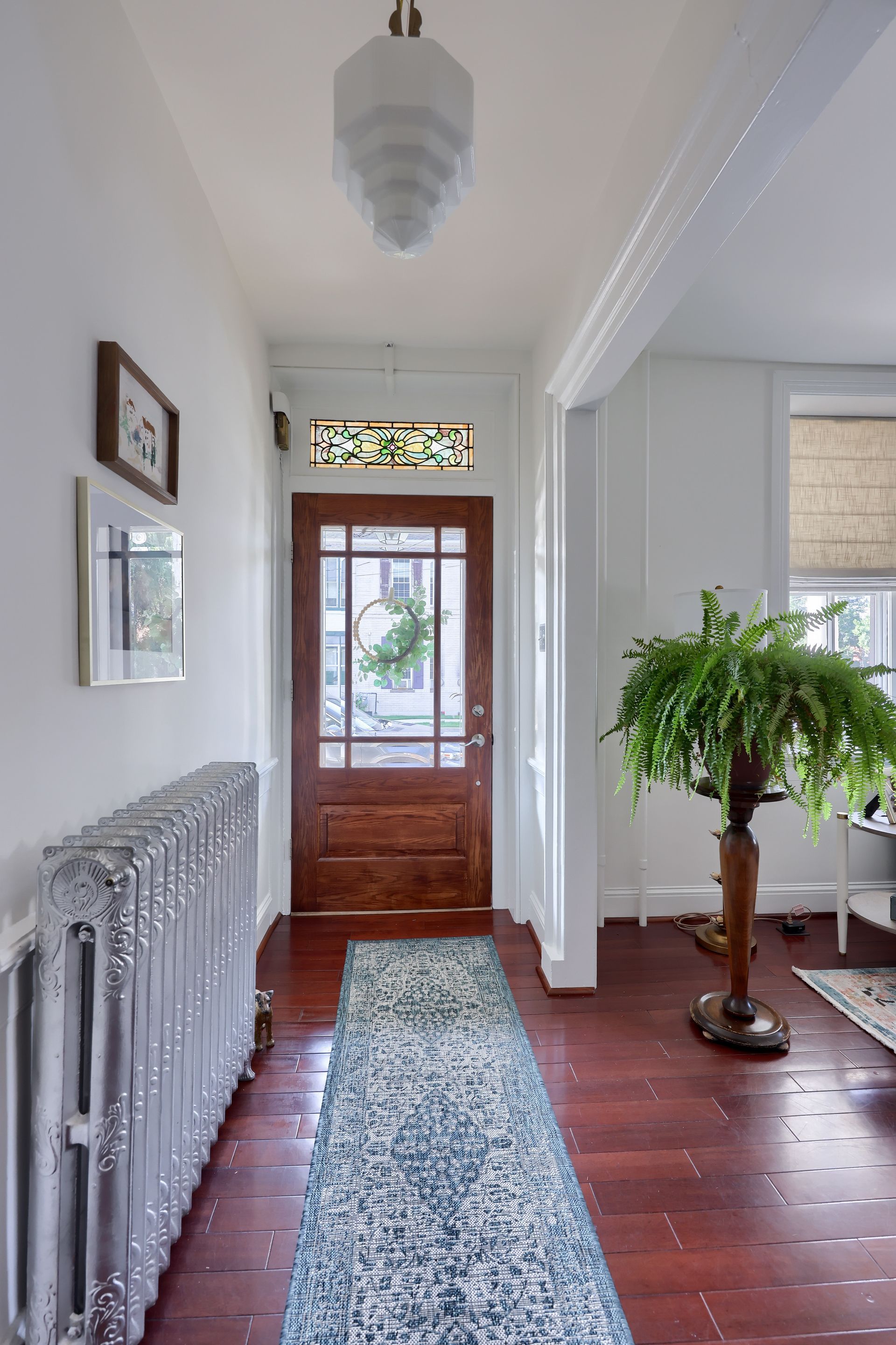 A hallway with a rug and a radiator in a house.