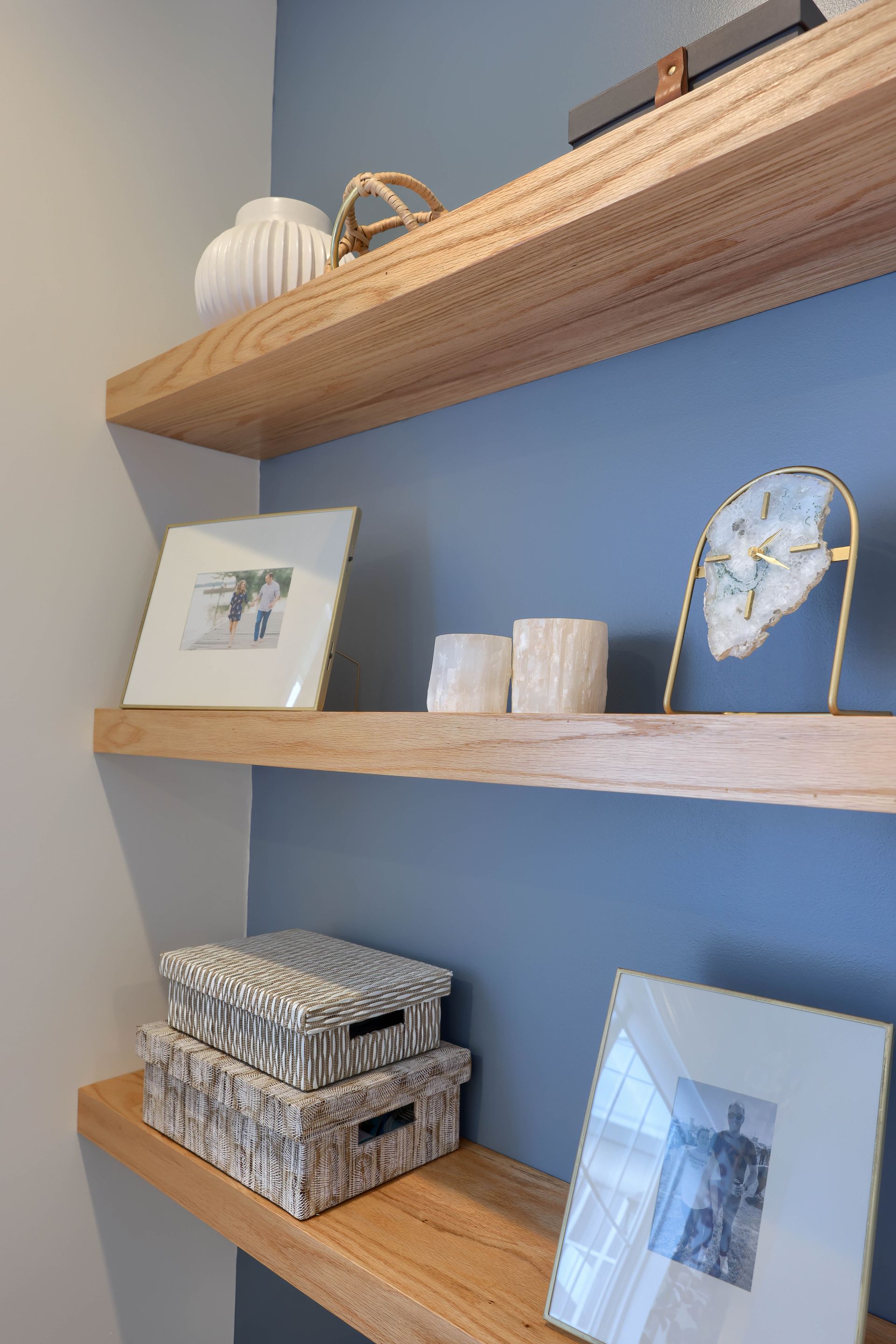 A wooden shelf with boxes and pictures on it in a room.