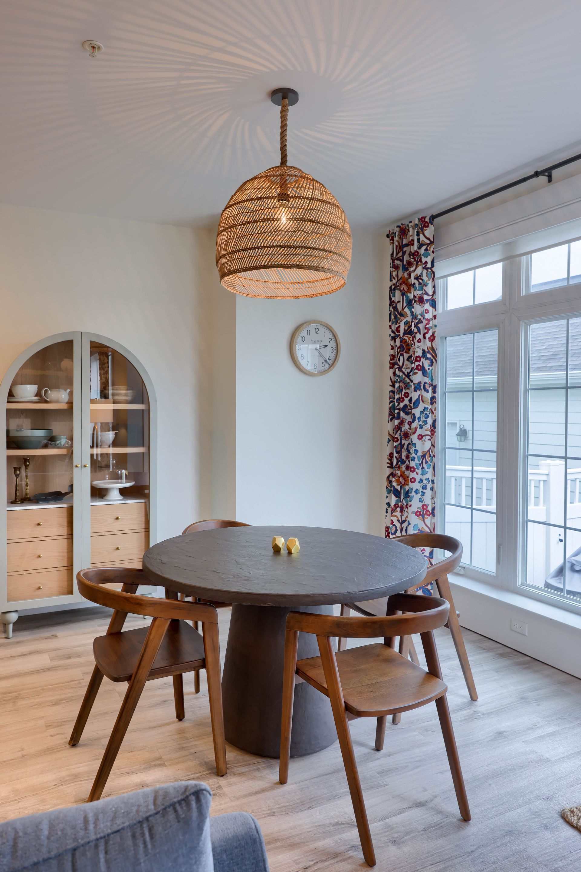A dining room with a table and chairs and a clock on the wall.