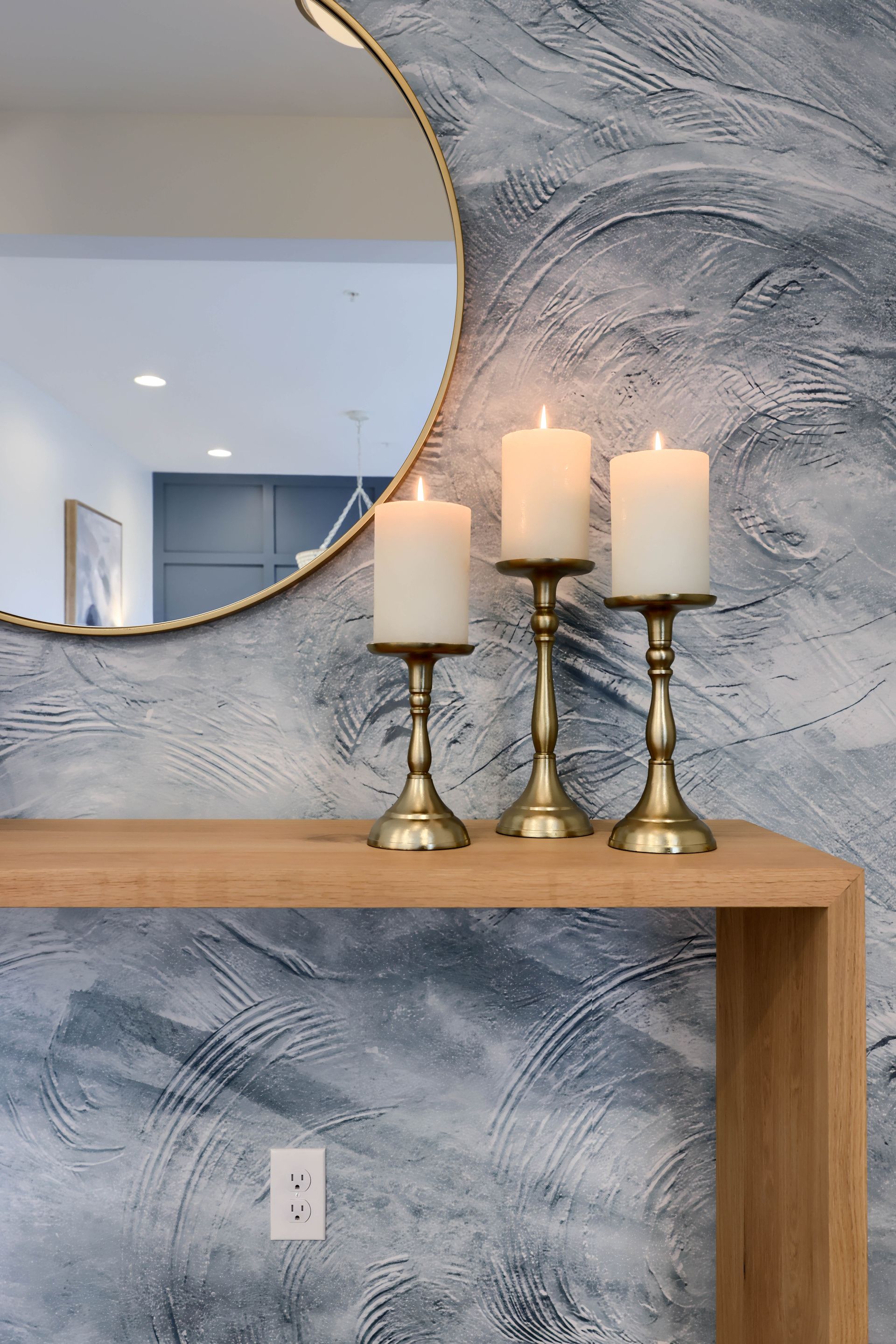 Three candles are sitting on a wooden table in front of a mirror.