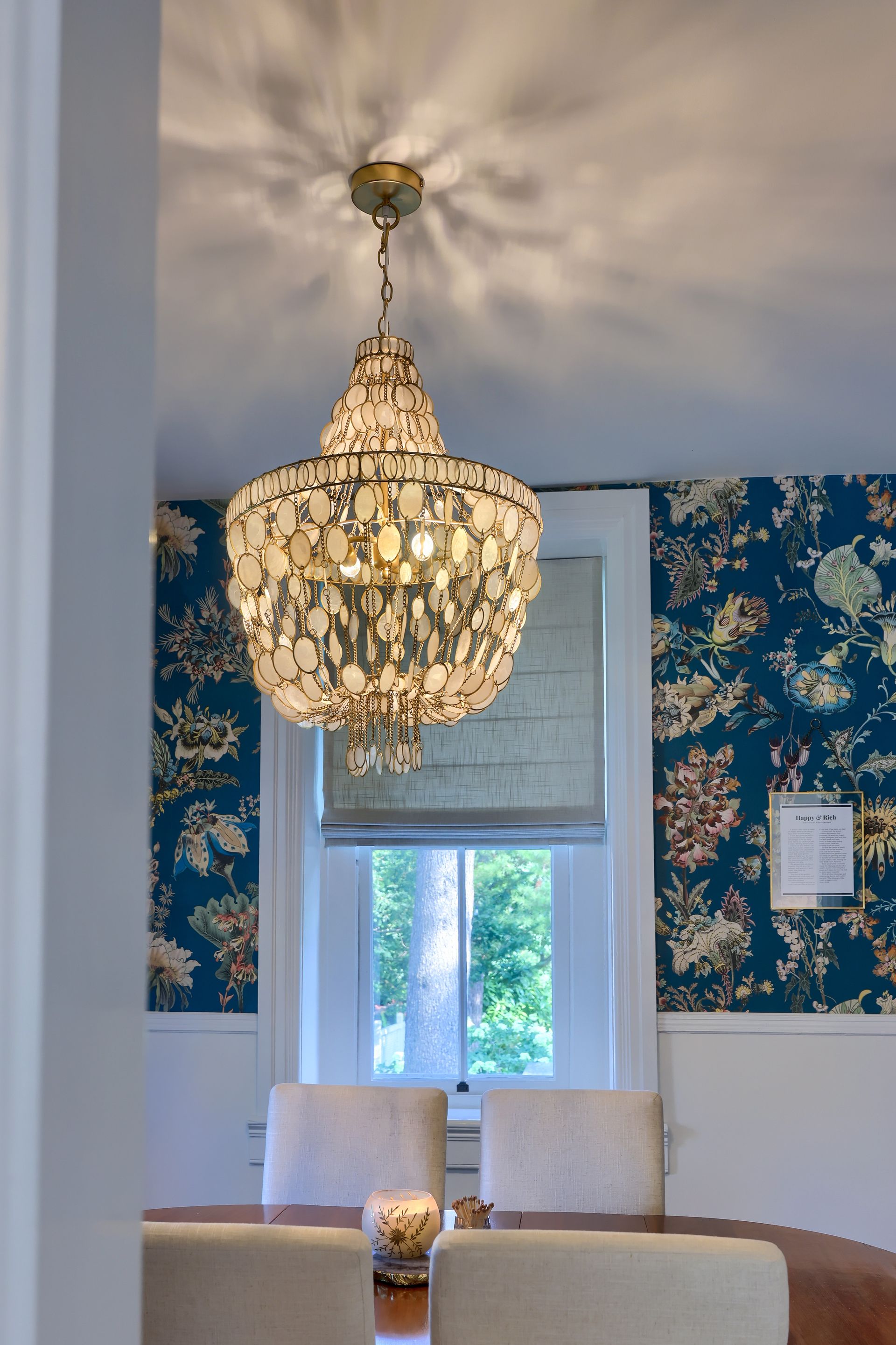 A dining room with a table and chairs and a chandelier hanging from the ceiling.