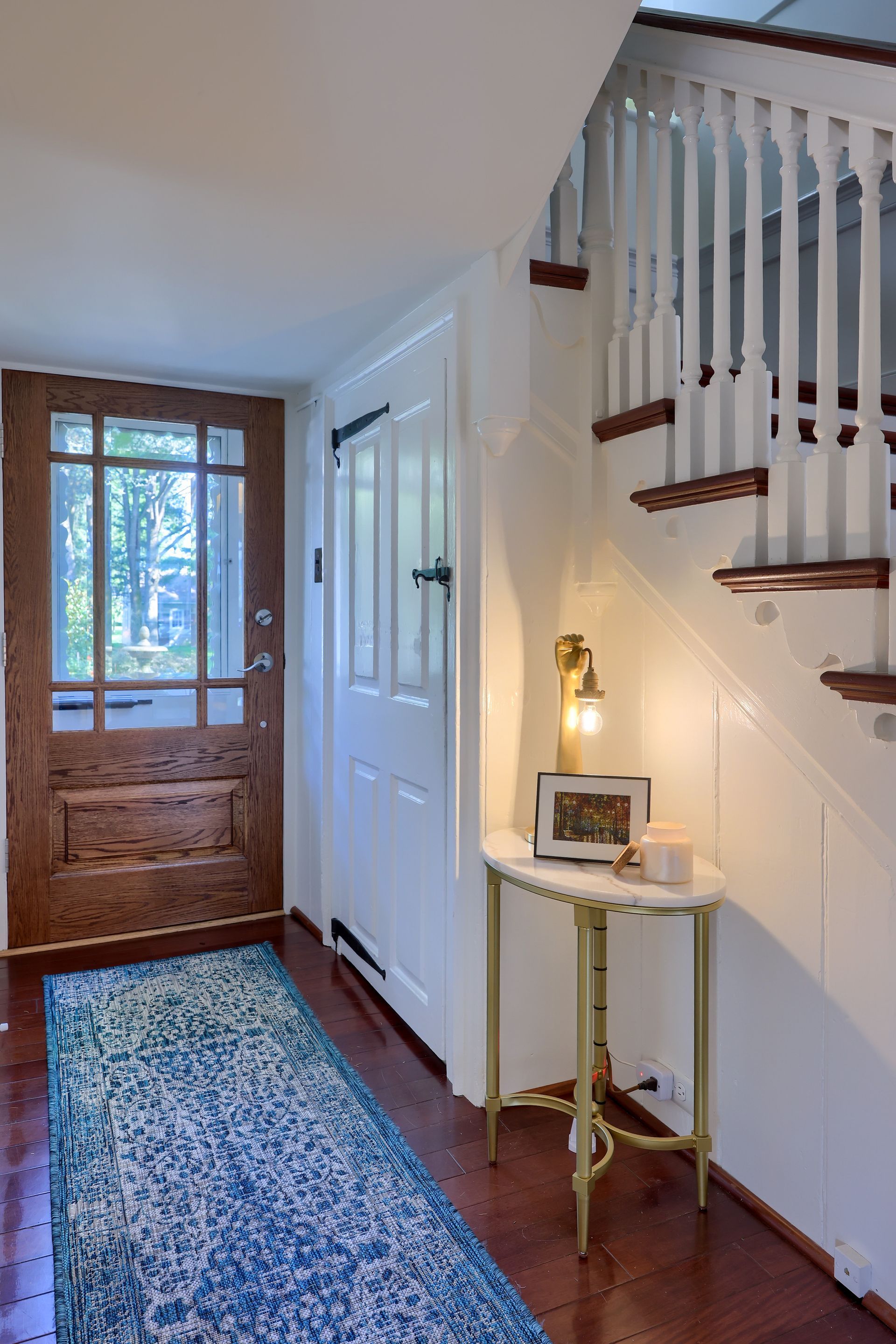 A hallway with a wooden door and stairs leading up to the second floor.