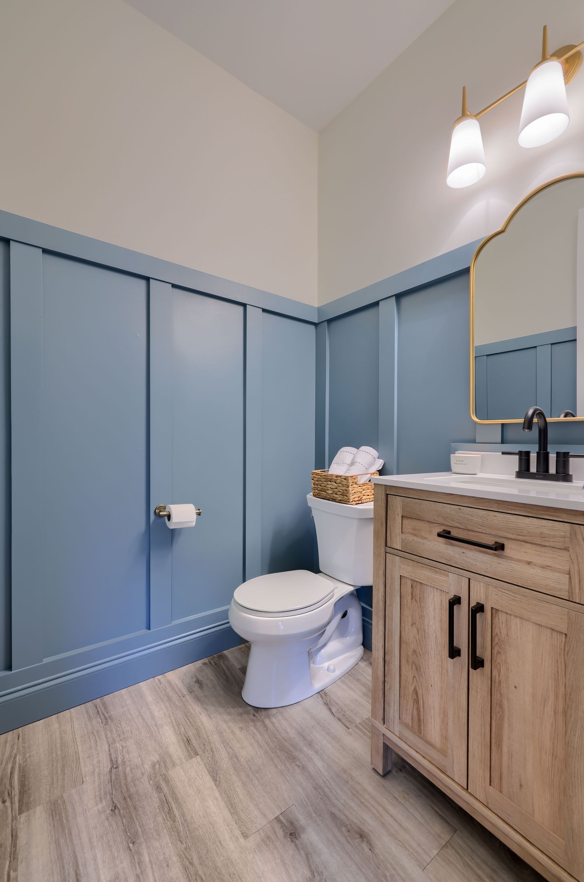A bathroom with blue walls , a toilet , a sink , and a mirror.