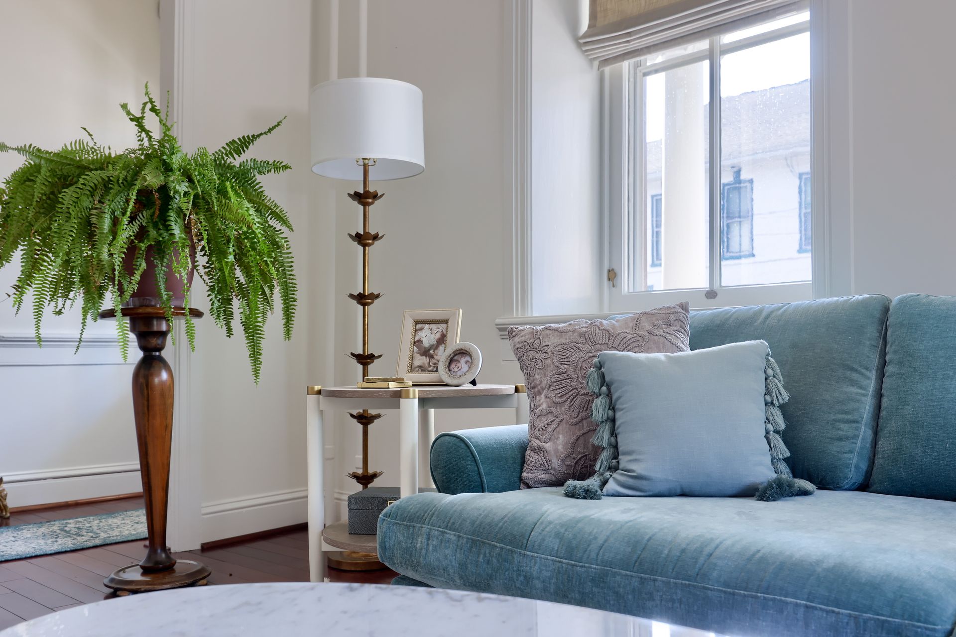 A living room with a couch , lamp , table and potted plant.
