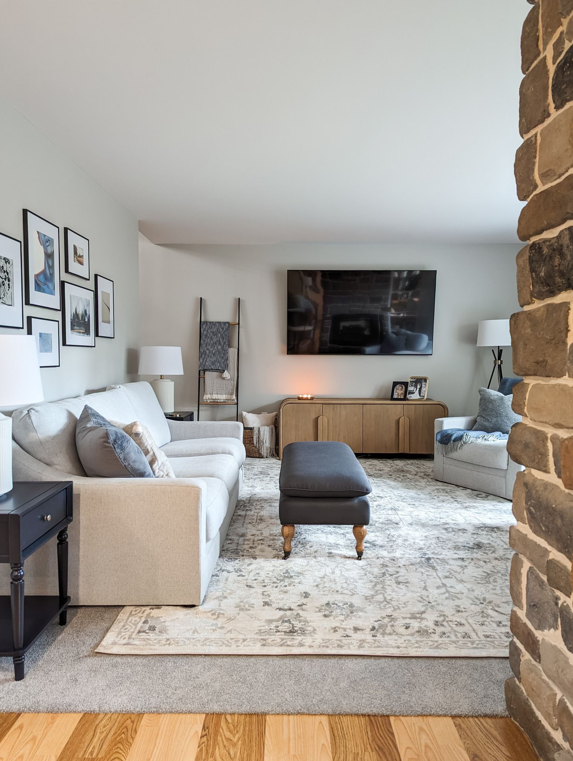 Living room with light sofa, curved wood console and gallery wall