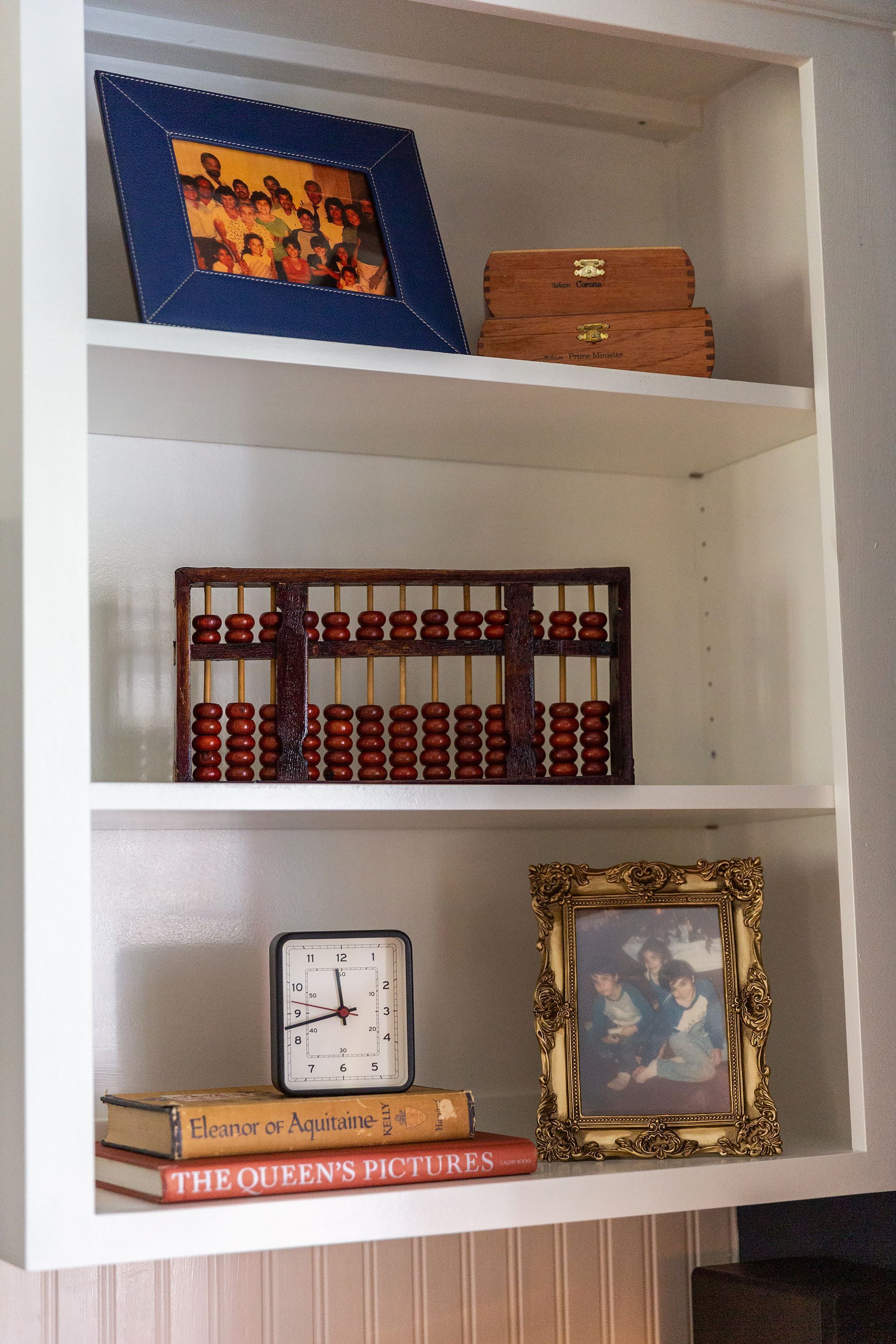 A shelf with a clock a book and a picture frame