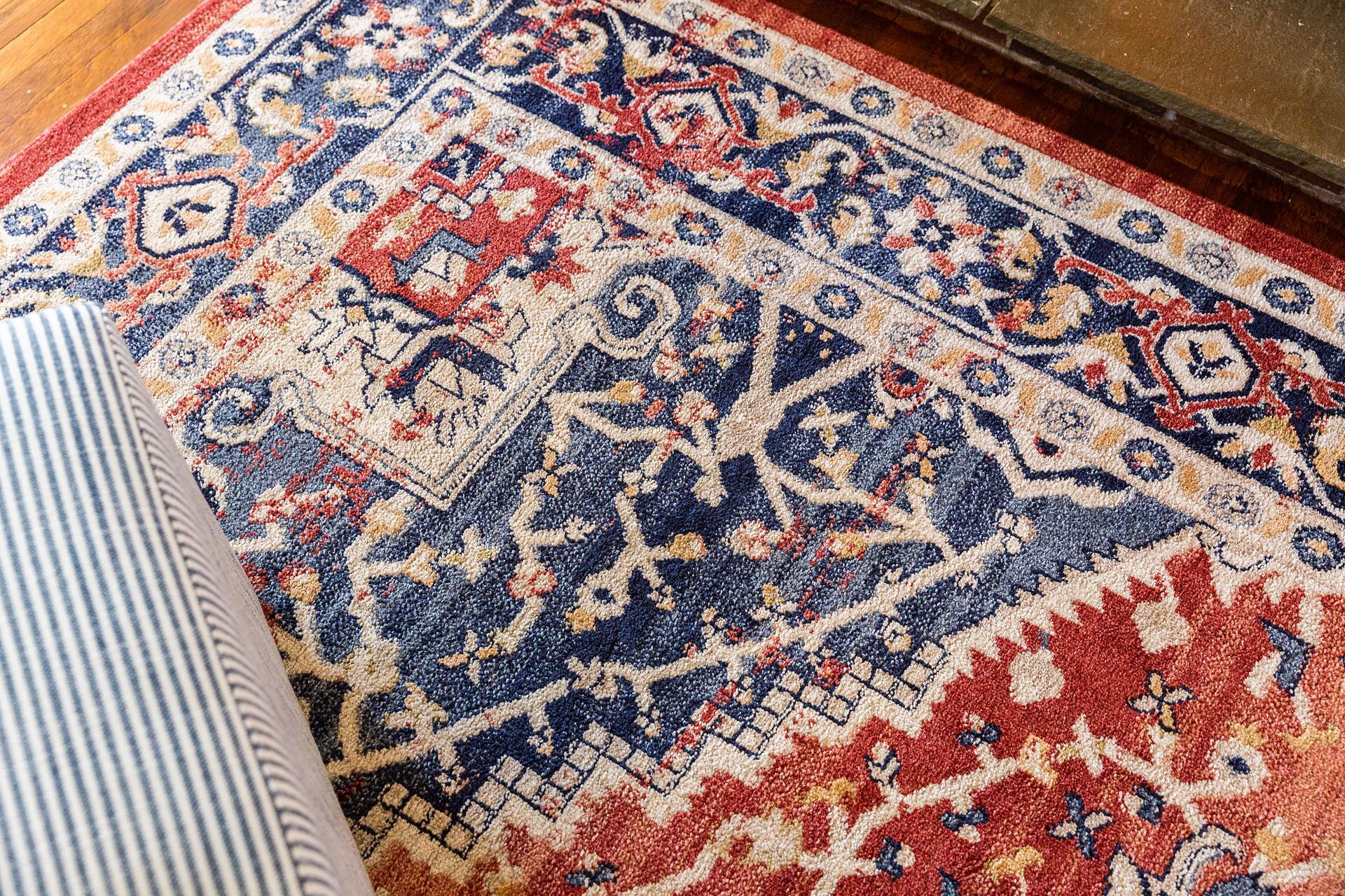 A red , white and blue rug is sitting on a wooden floor.
