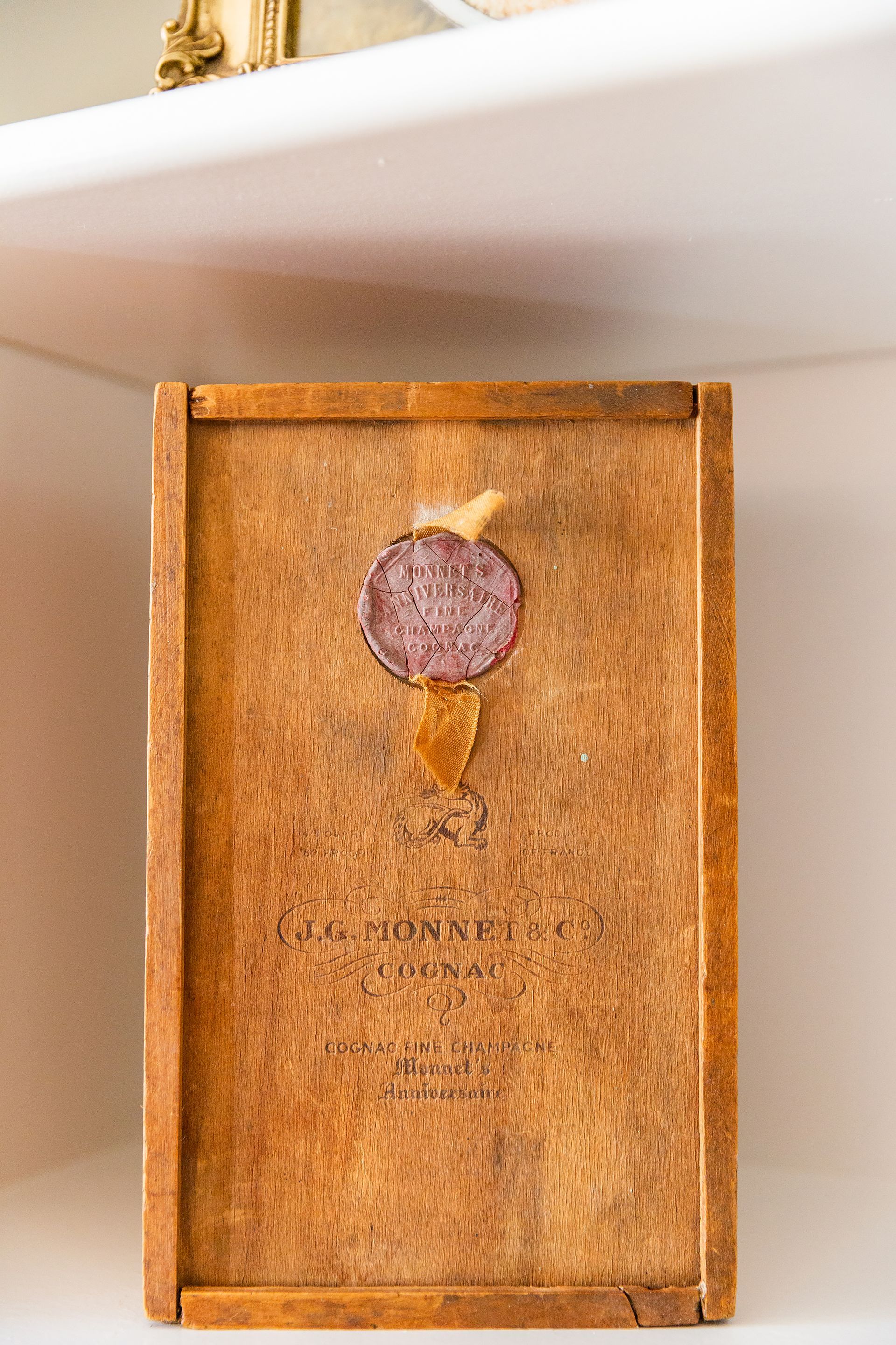A wooden box with a seal on it is sitting on a shelf.
