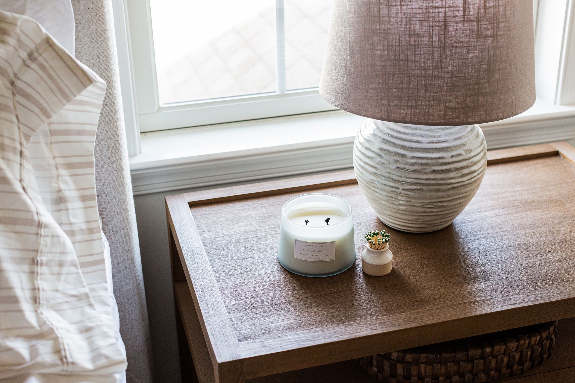 A nightstand with a lamp , candle and ring on it.