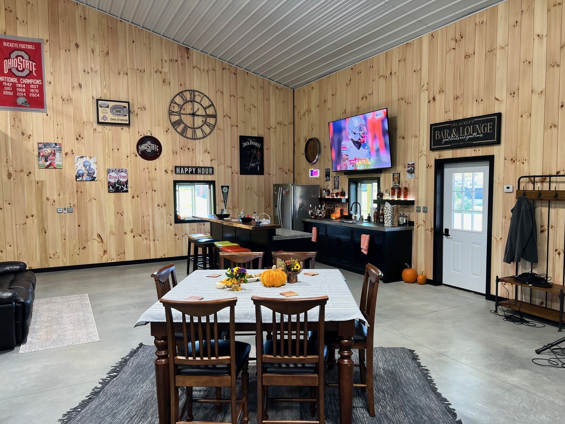 Interior of a large room with wood paneling, a table set for a meal, a bar, and a television.