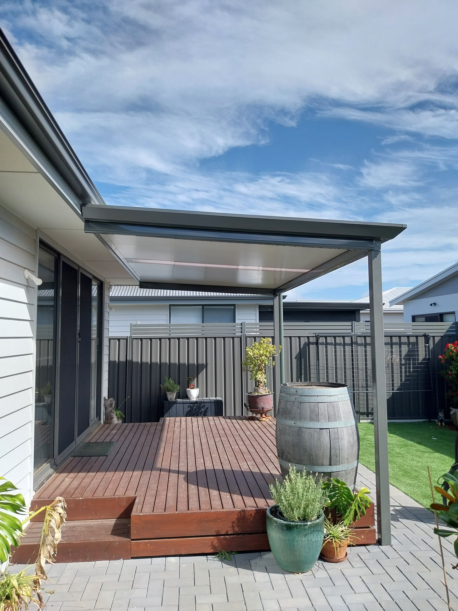 Modern kitchen with island, stools, skylights, stainless steel appliances, and a door to the garden.