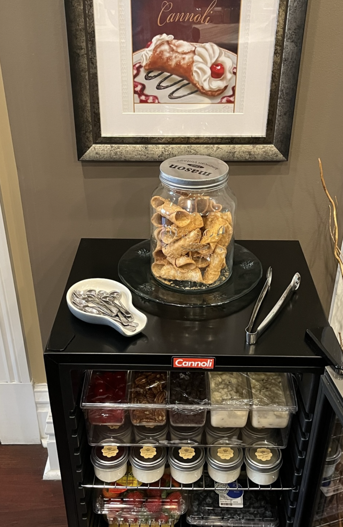 A glass dome filled with brownies is on a wooden table.