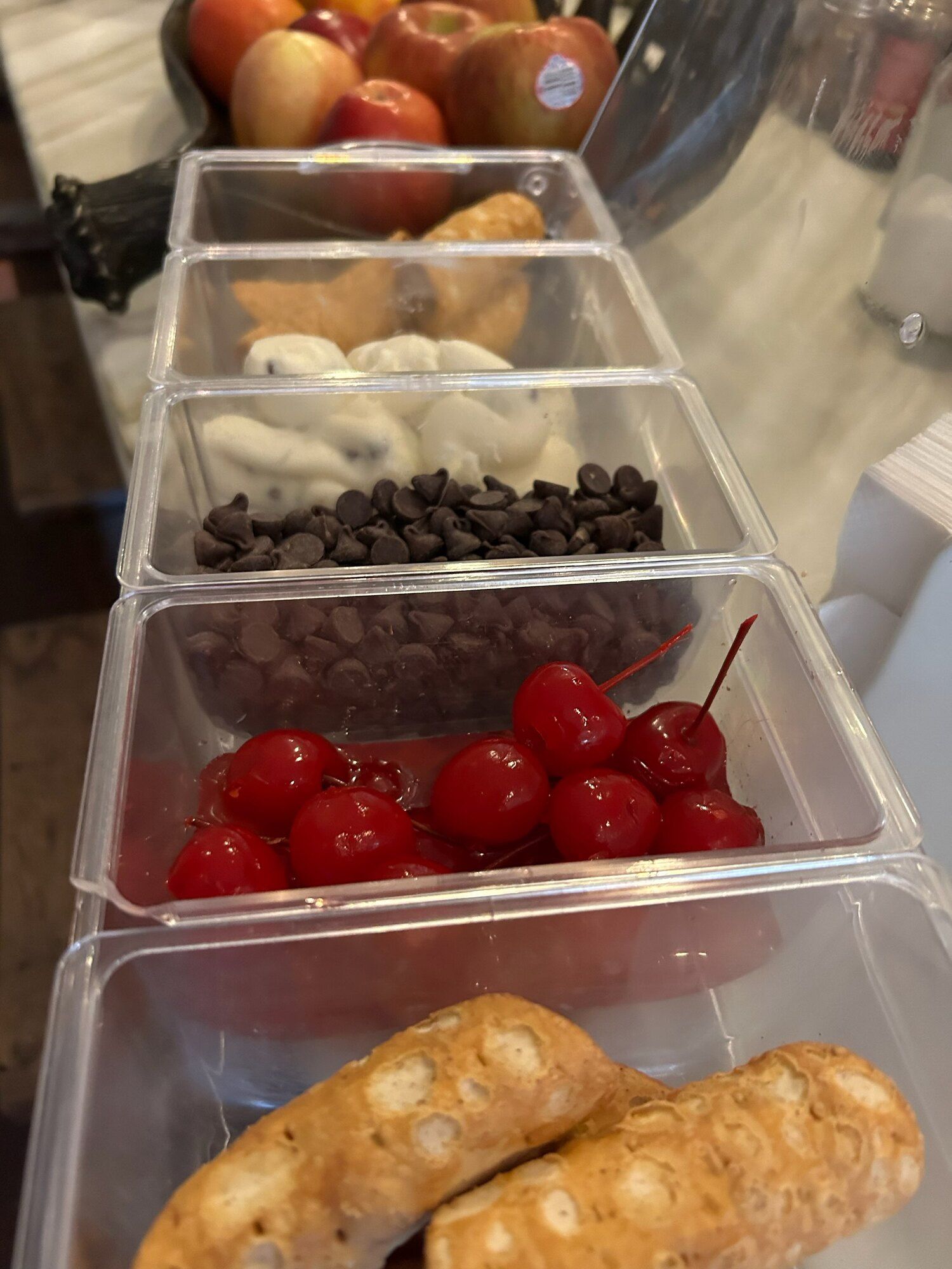 A tray of food with cherries , chocolate chips , and cannoli on a table.