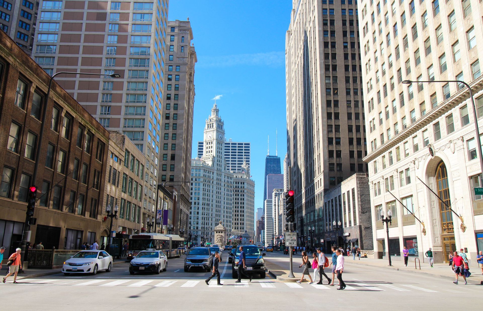 A city street with a lot of buildings and people crossing the street.