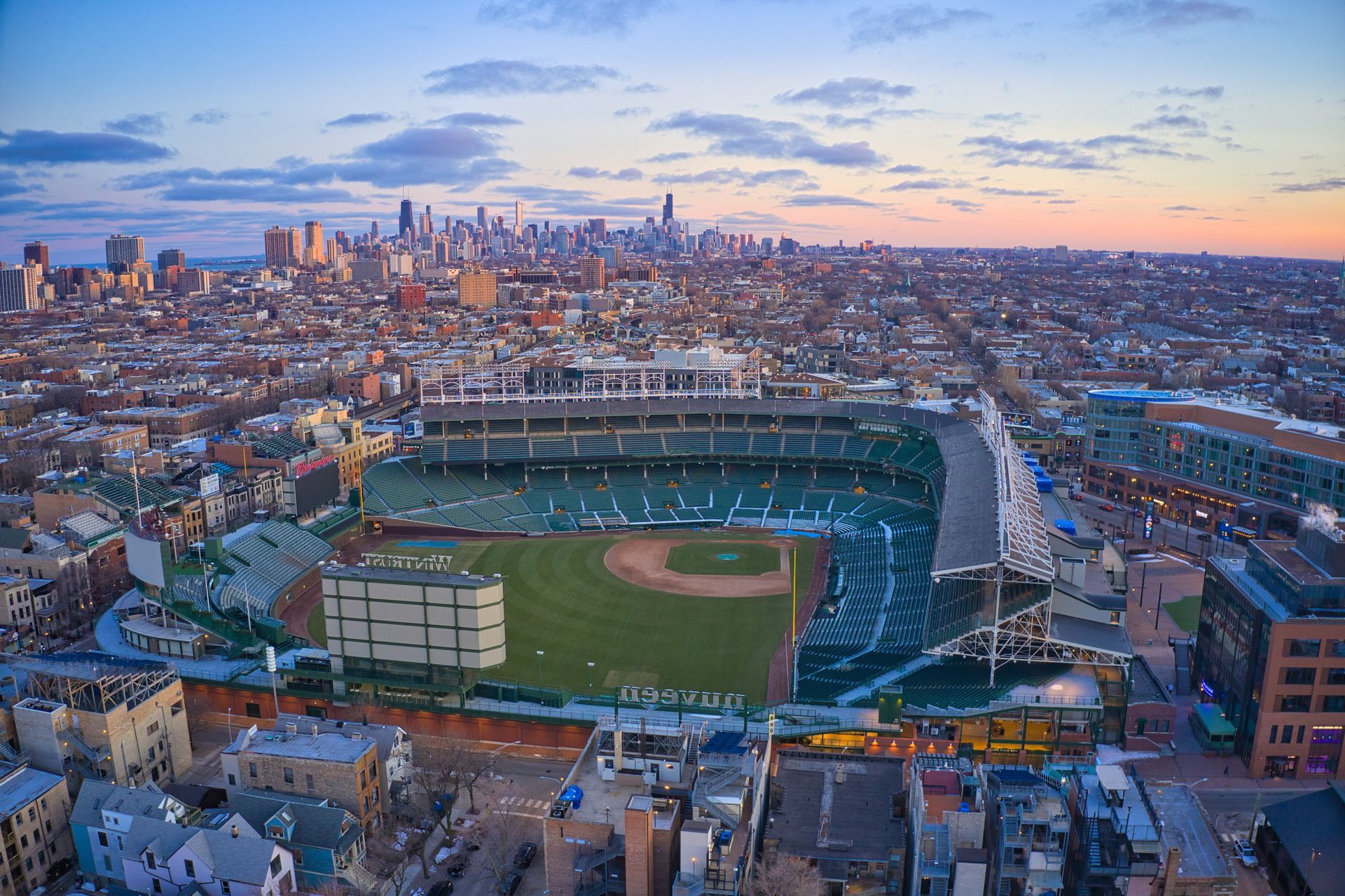 An aerial view of a baseball stadium in a city with a city skyline in the background.