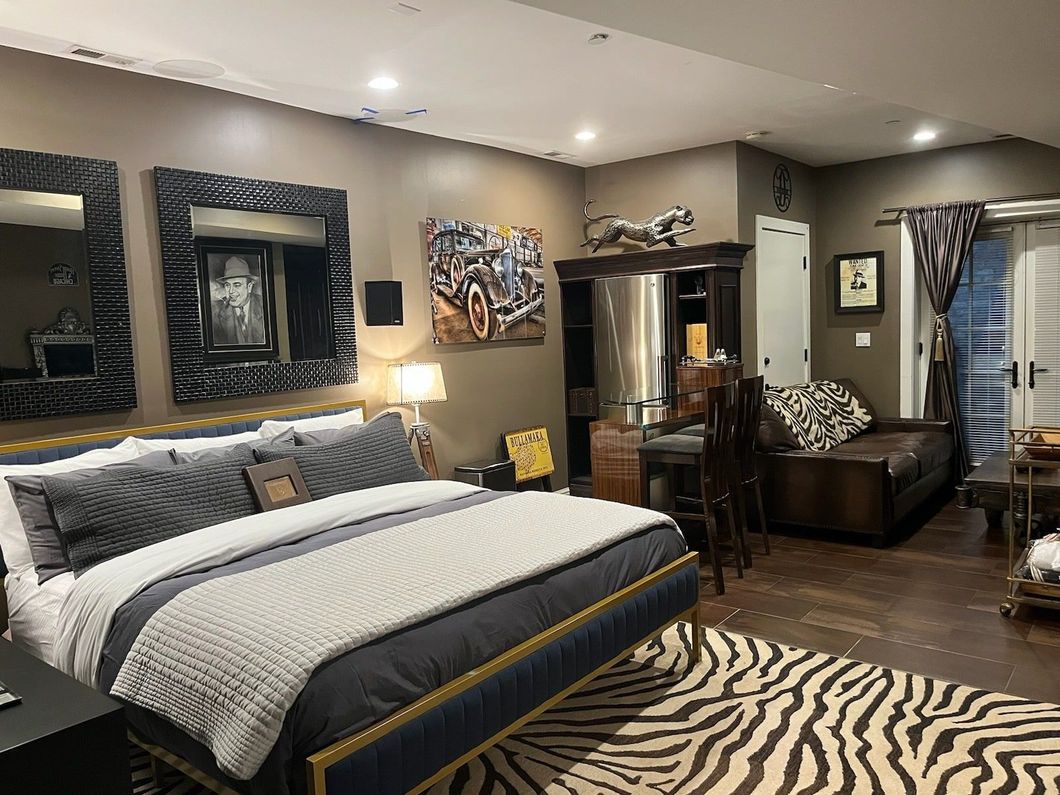 A bedroom with a large bed and a zebra print rug.