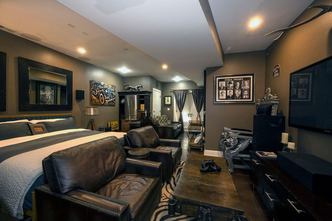 A living room with a bed , chairs , a coffee table and a television.