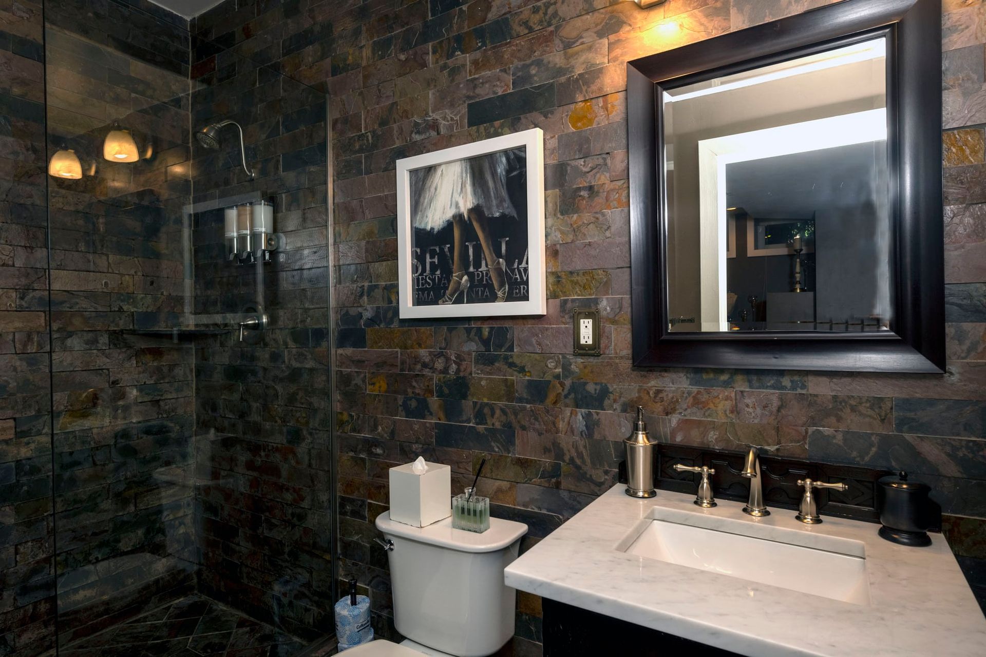 A bathroom with a toilet , sink , mirror and shower.