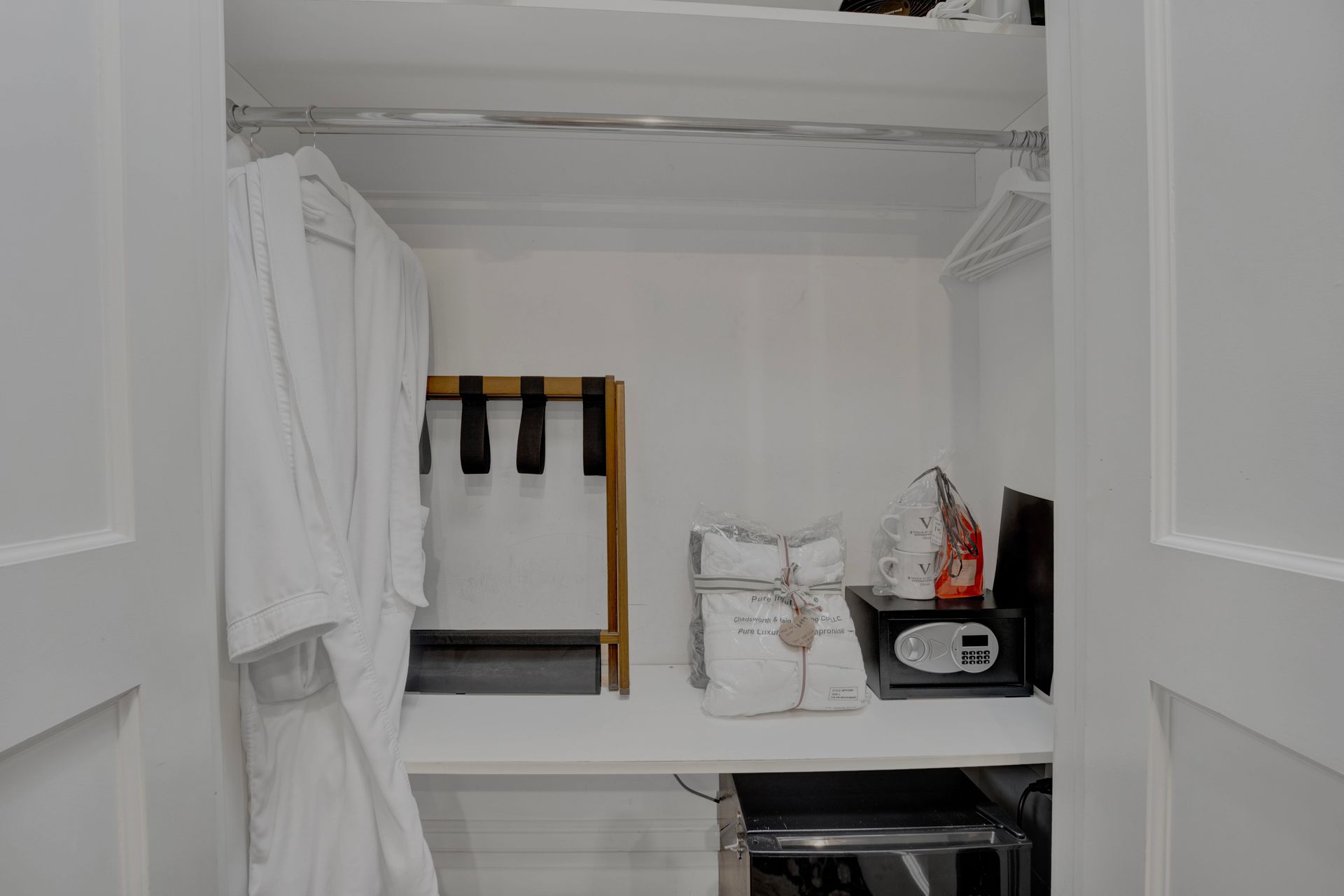 A closet in a hotel room with a robe and a safe.