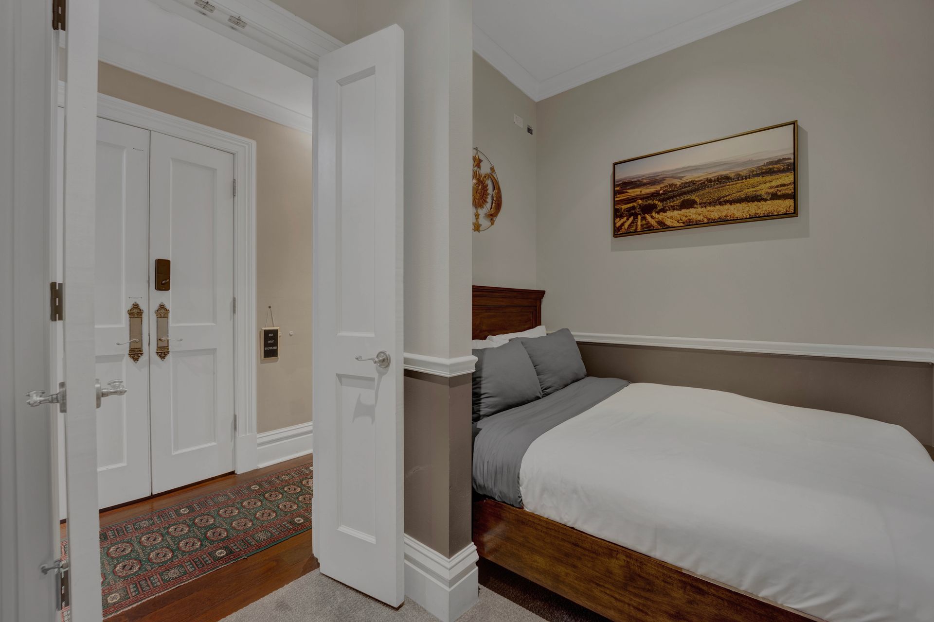 A bedroom with a bed and a painting on the wall.