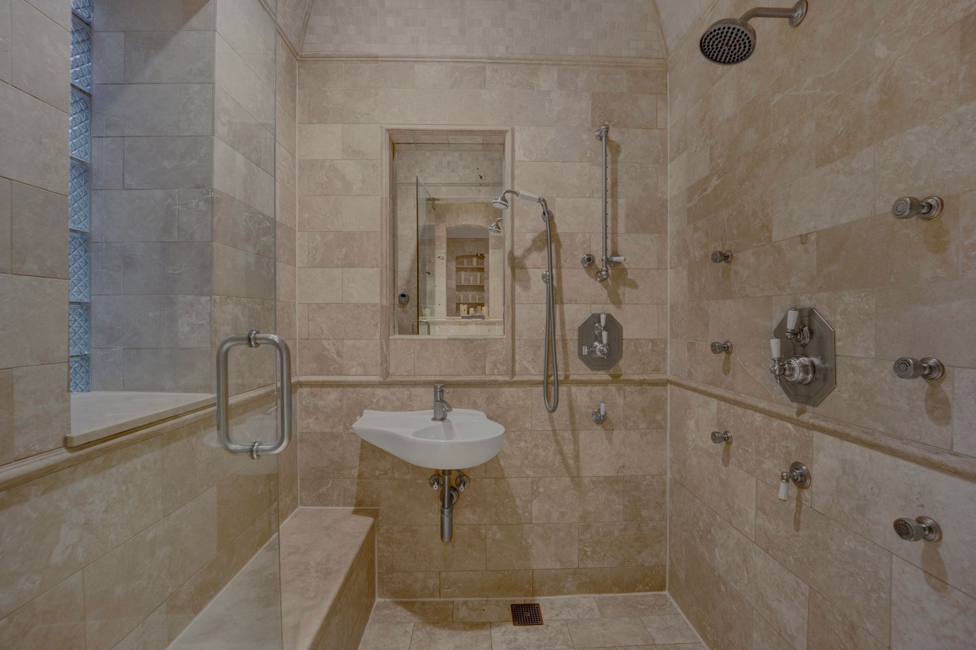 A bathroom with a sink , shower and mirror.